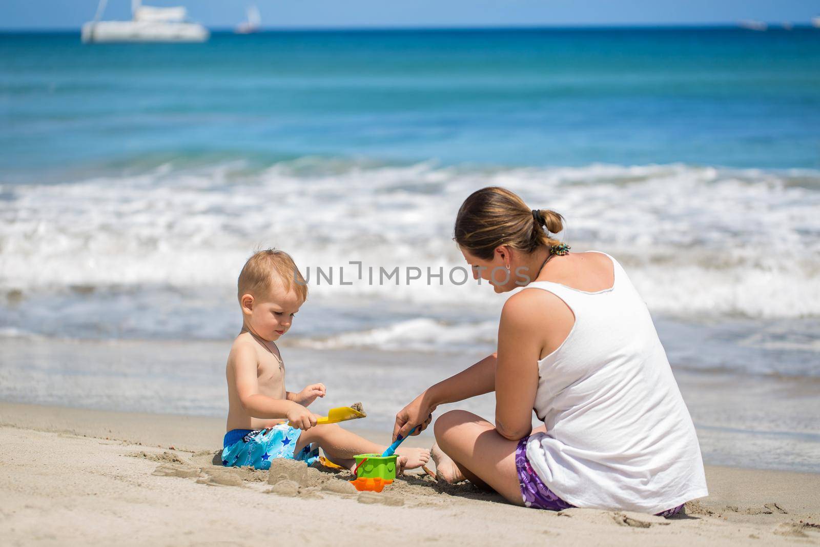 mother and son build sand castle on the beach