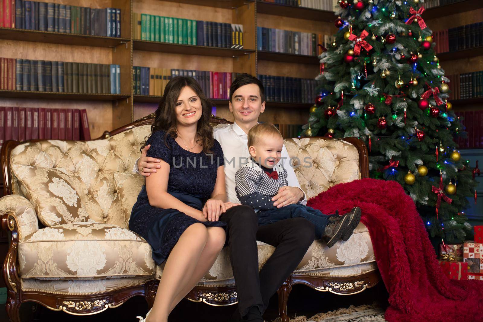 Family. Dad, mom and little son sitting on the sofa near the Christmas tree.