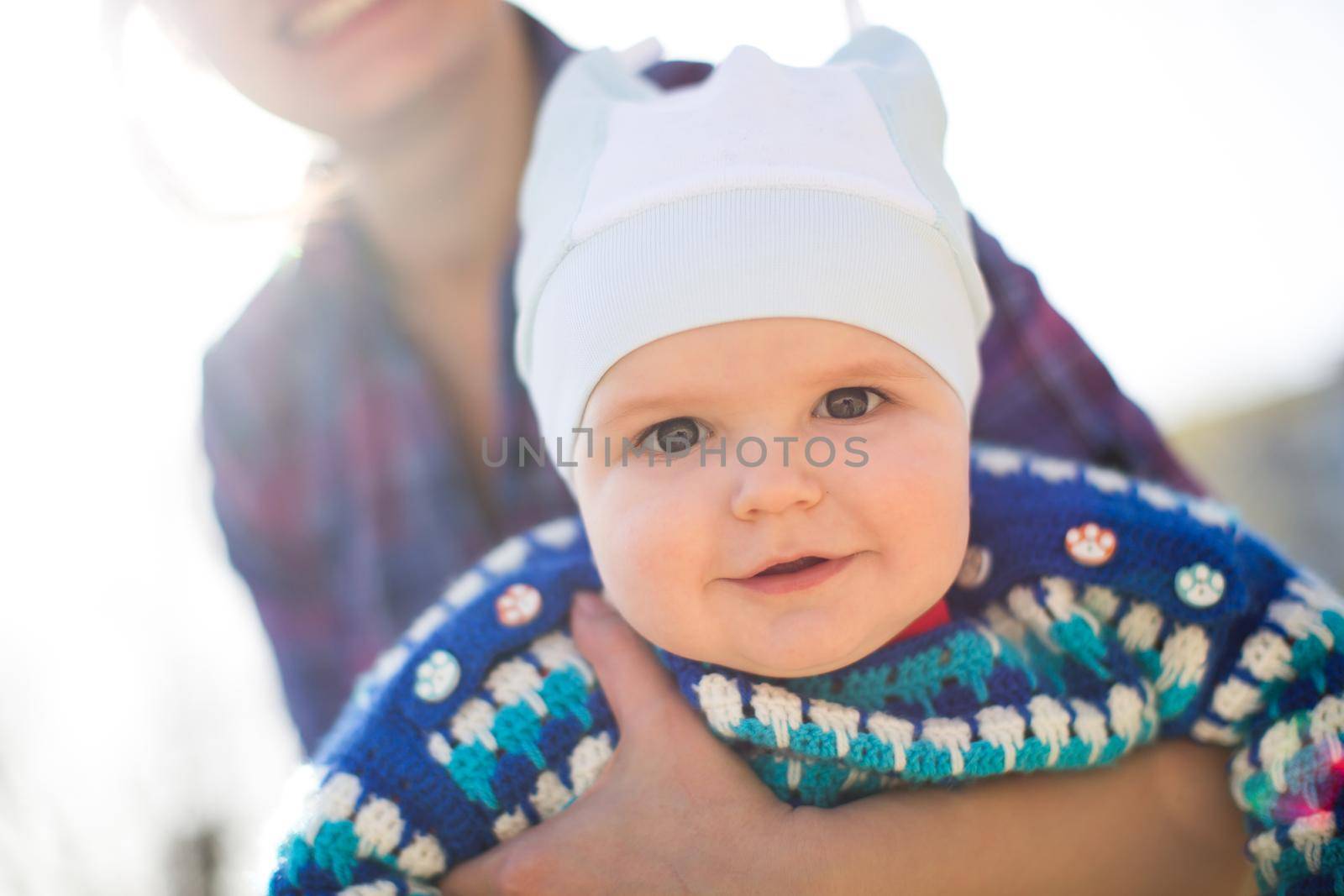 Portrait of smiling mother and baby outdoors. by StudioPeace