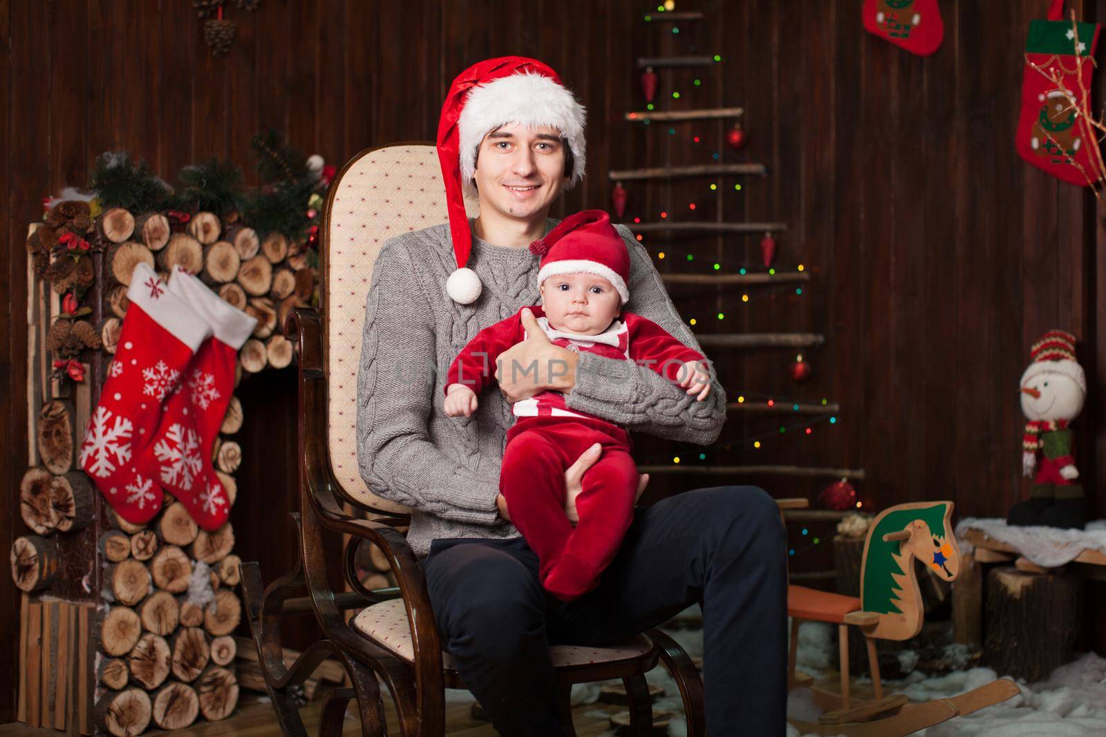 A man with a child dressed as Santa Claus on an armchair by a wooden fireplace on New Year's Eve
