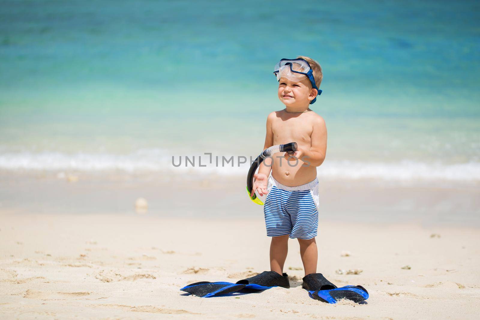 Little boy with diving mask and fins go swim at beach