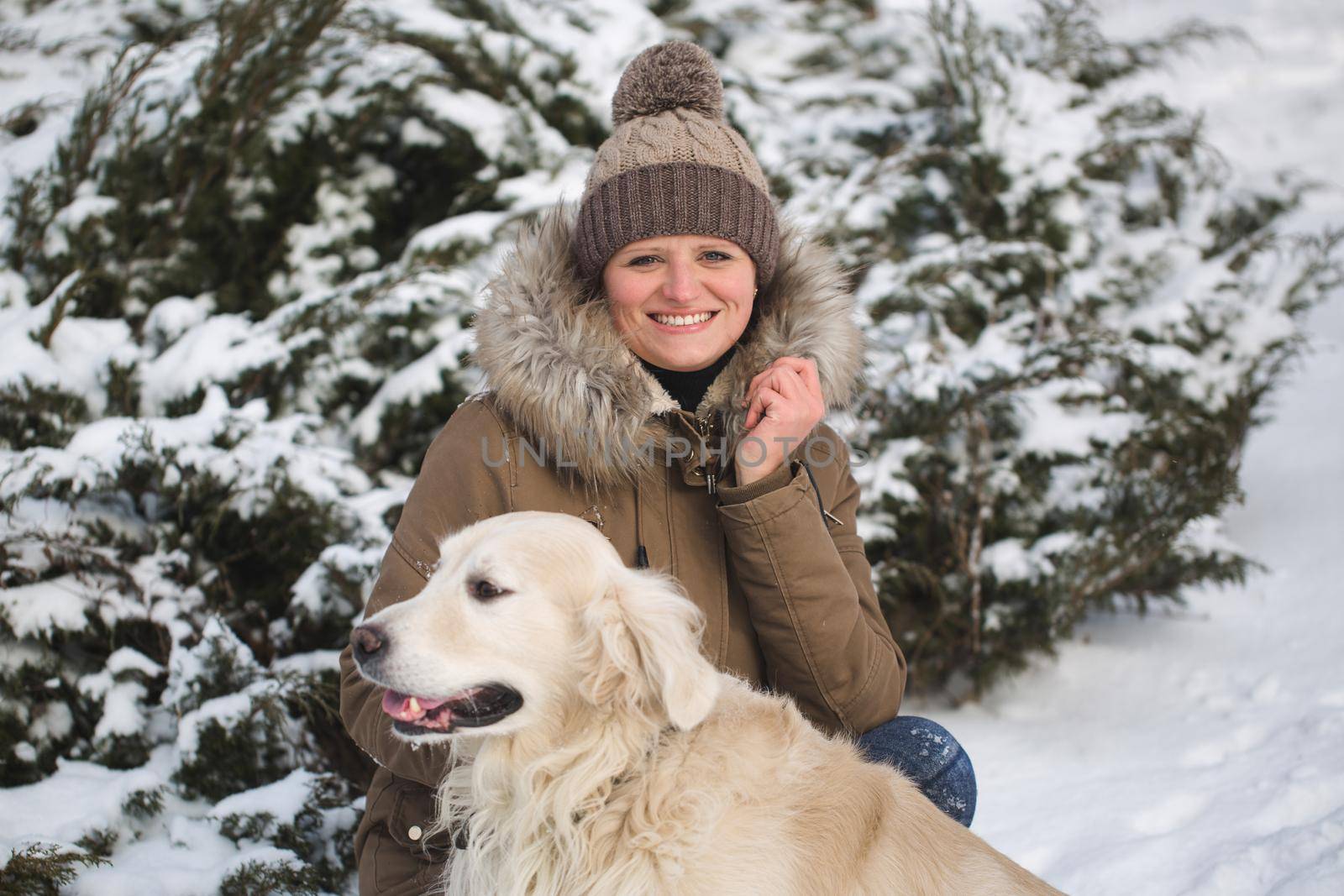 Beautiful girl playing with her dog in the snow. Golden Retriever