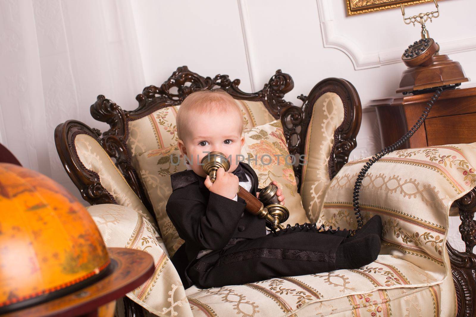 Child in a tuxedo sitting in an office talking on the phone by StudioPeace