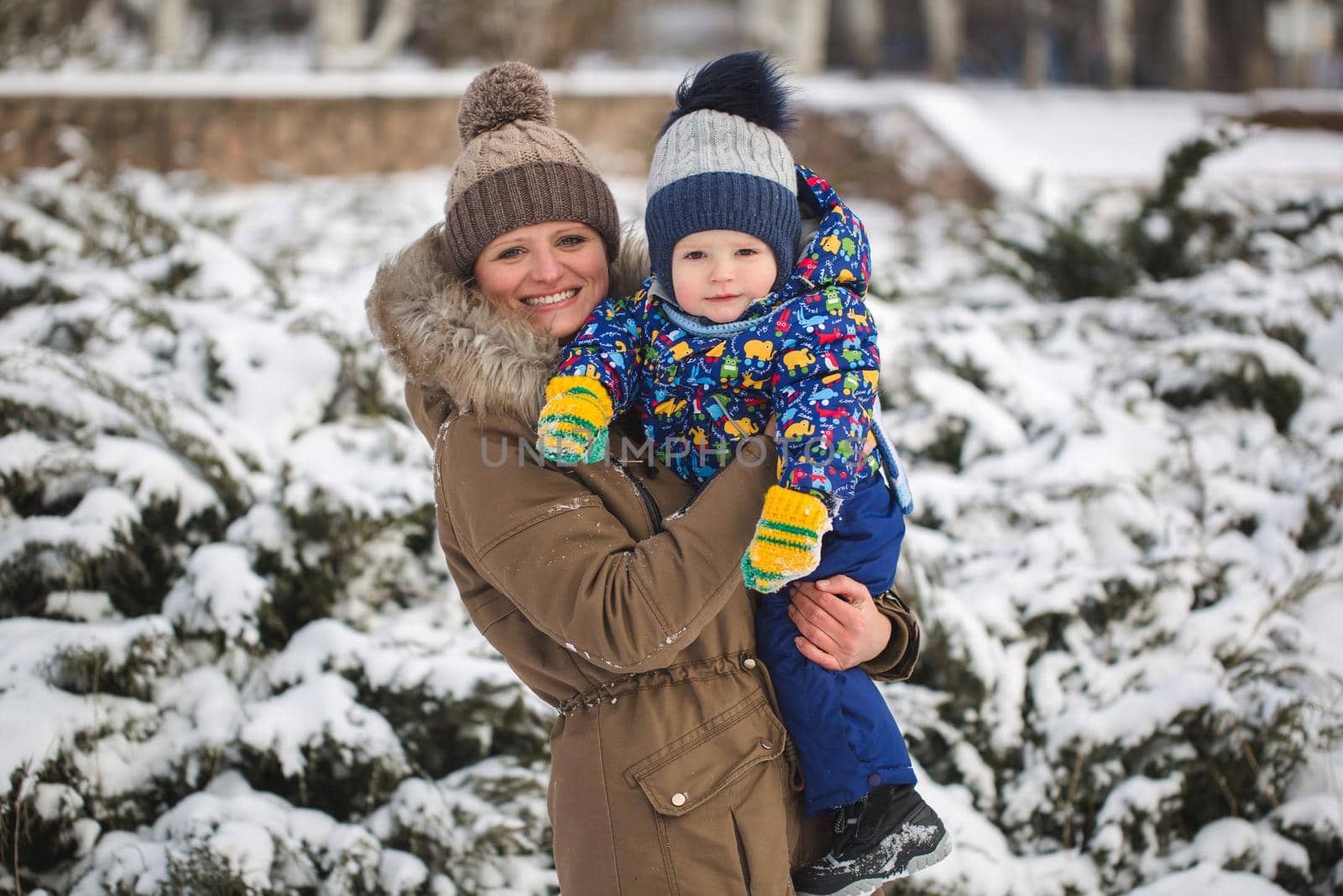 happy mother and baby in winter park. family outdoors. cheerful mommy with her child