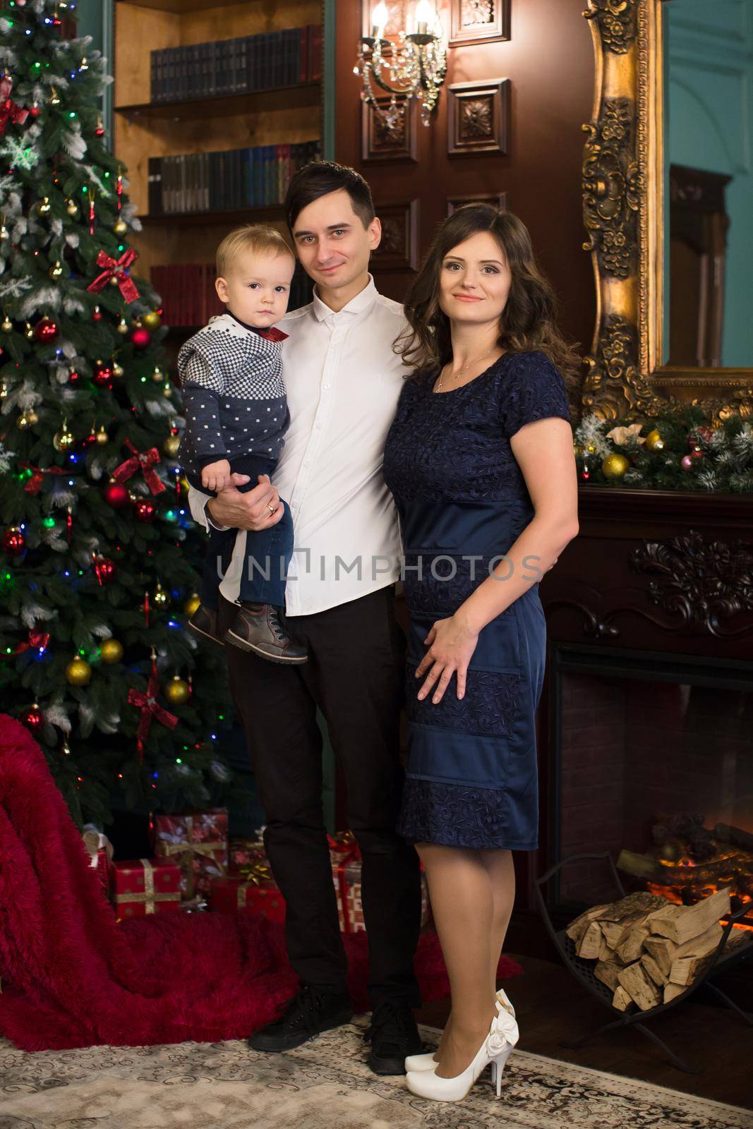 Family sitting together in a Christmas interior. Happy family have fun with Christmas gifts. Christmas family portrait, mother, father and son celebrate the occasion.