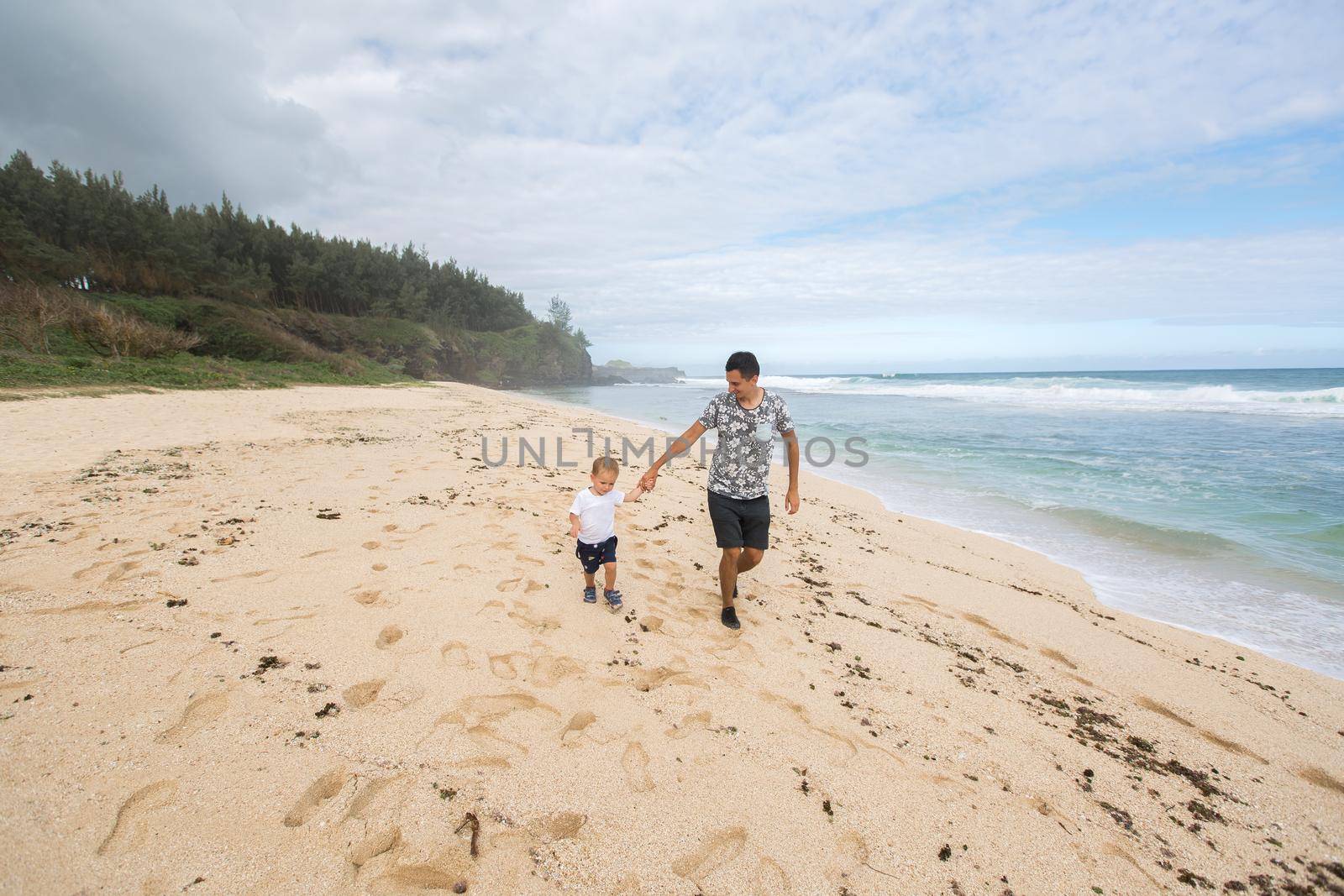 Father and Son Holding Hands Walking Together on the Beach. by StudioPeace