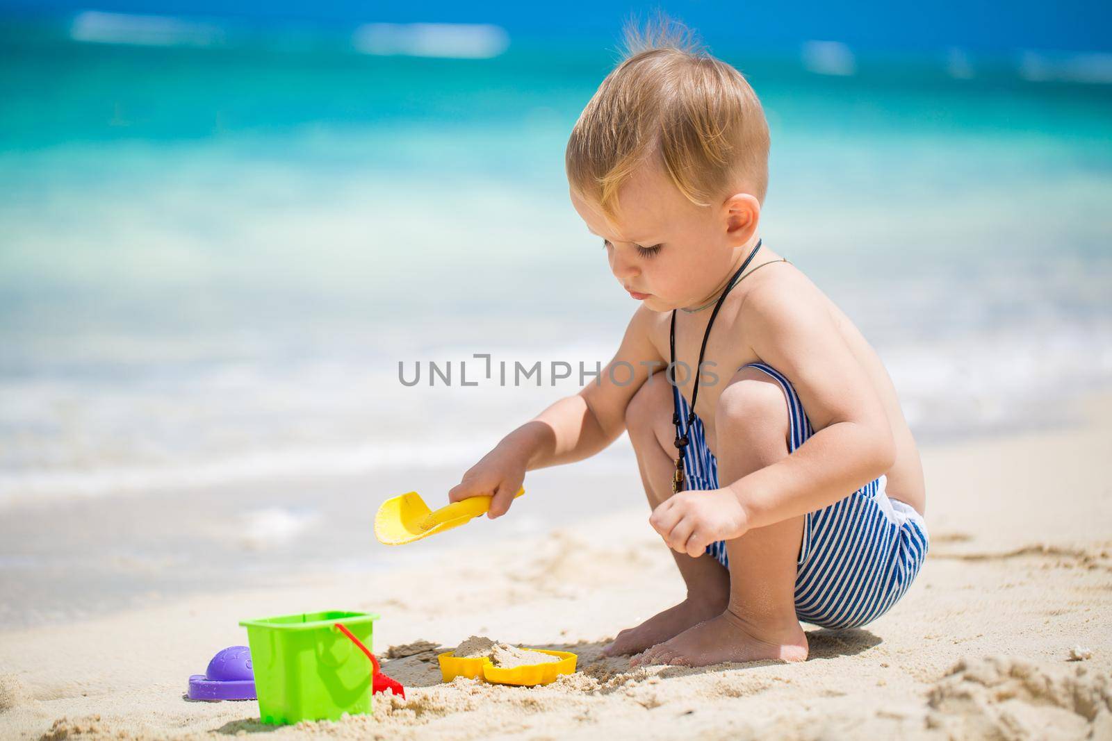 Cute baby boy playing with beach toys on tropical beach. by StudioPeace