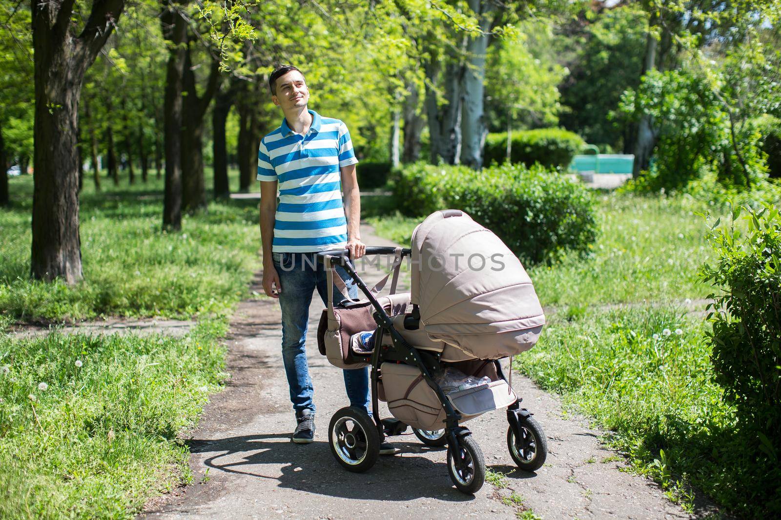 young man walking in an autumn park with a baby stroller. by StudioPeace
