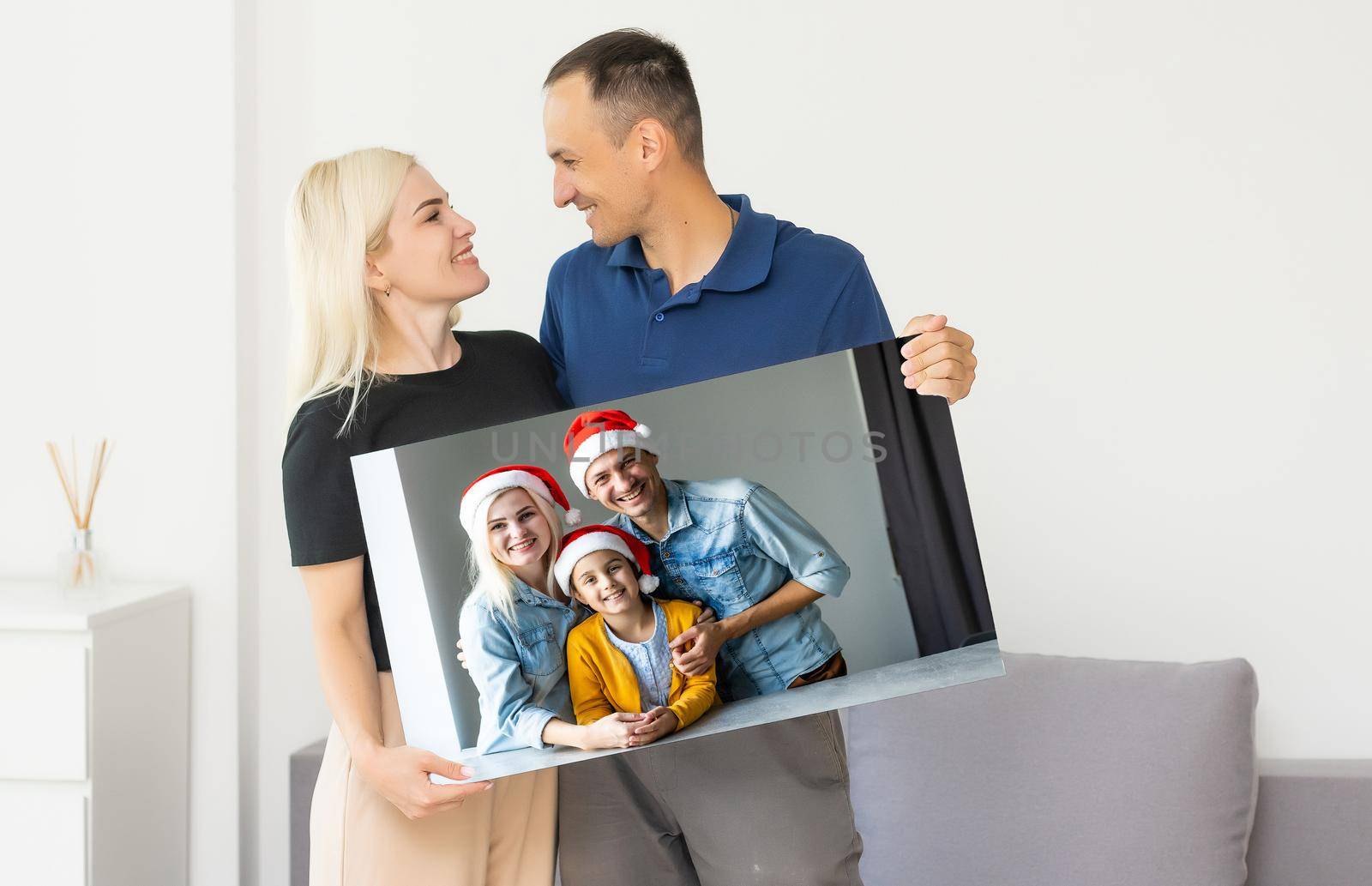 family holding photo canvas with christmas picture.