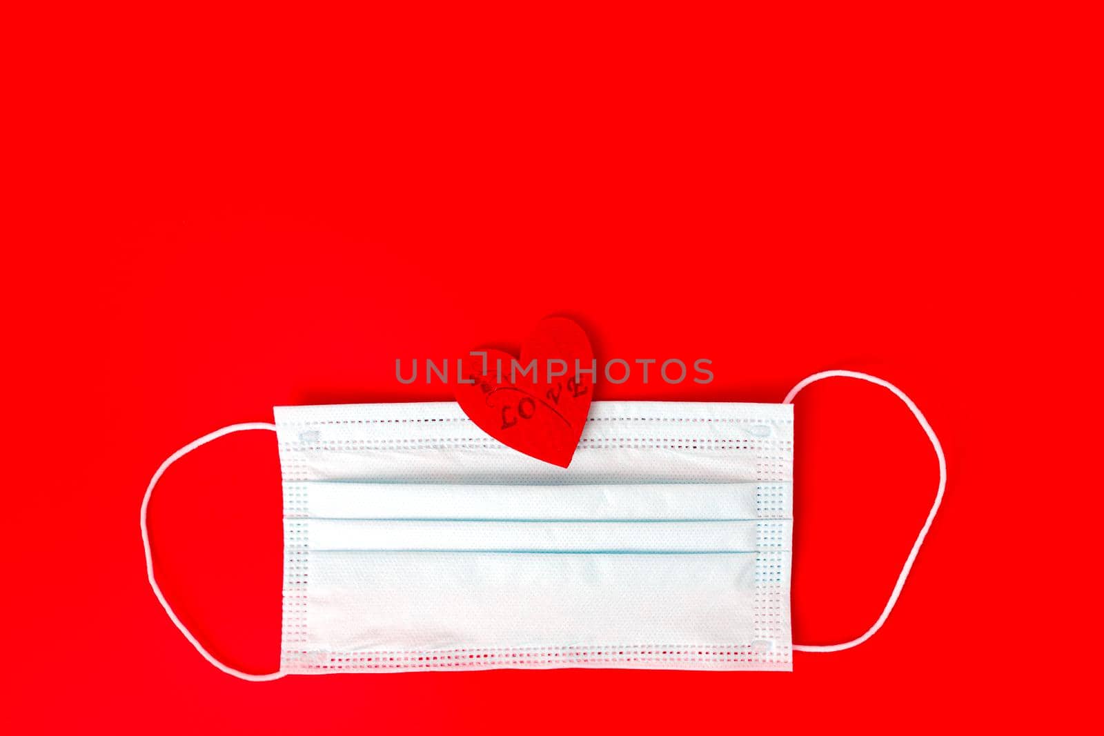 Medical face mask with red heart on red background . With copy space .Valentines day concept . by lifesummerlin