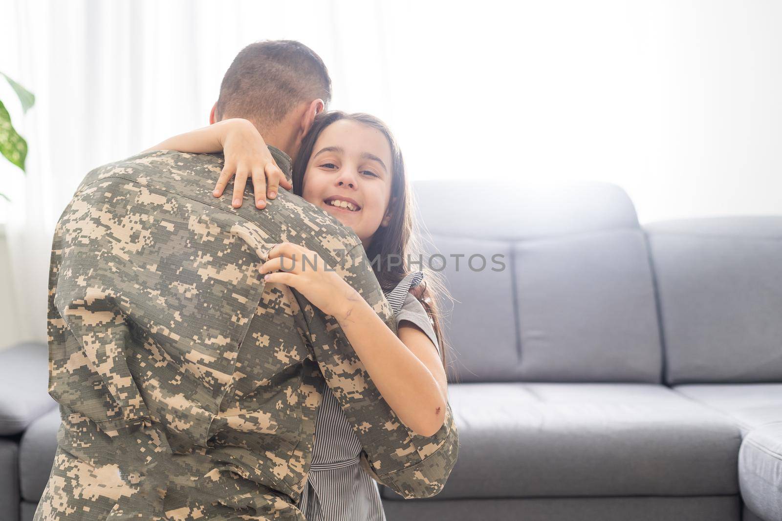 Little child is very happy her father came back from army. Little kid is hugging her father