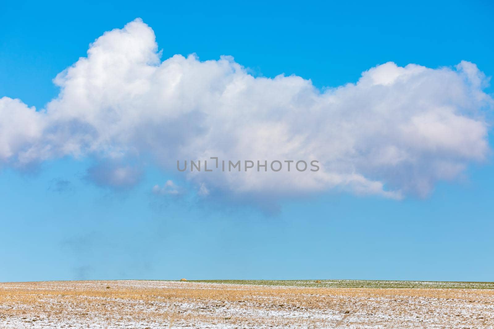 Simple winter background with beautiful lines from skier and big clouds on horizon with blue sky