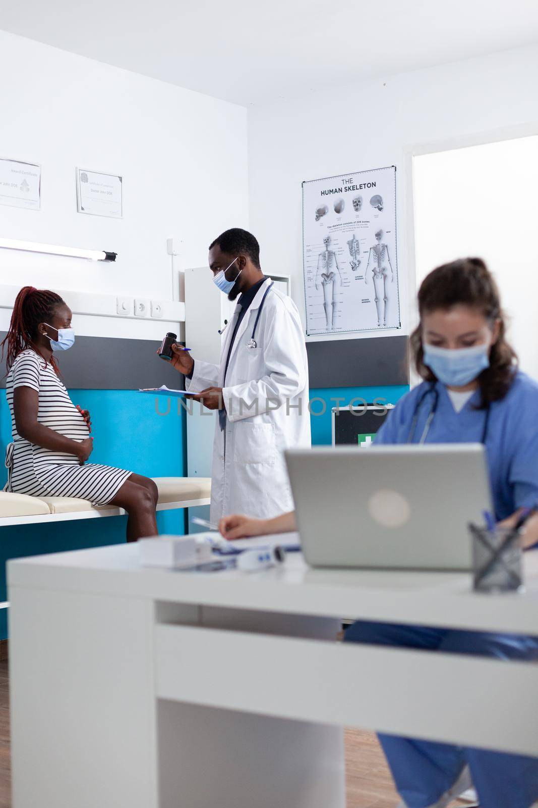 Doctor giving bottle of pills to pregnant woman by DCStudio