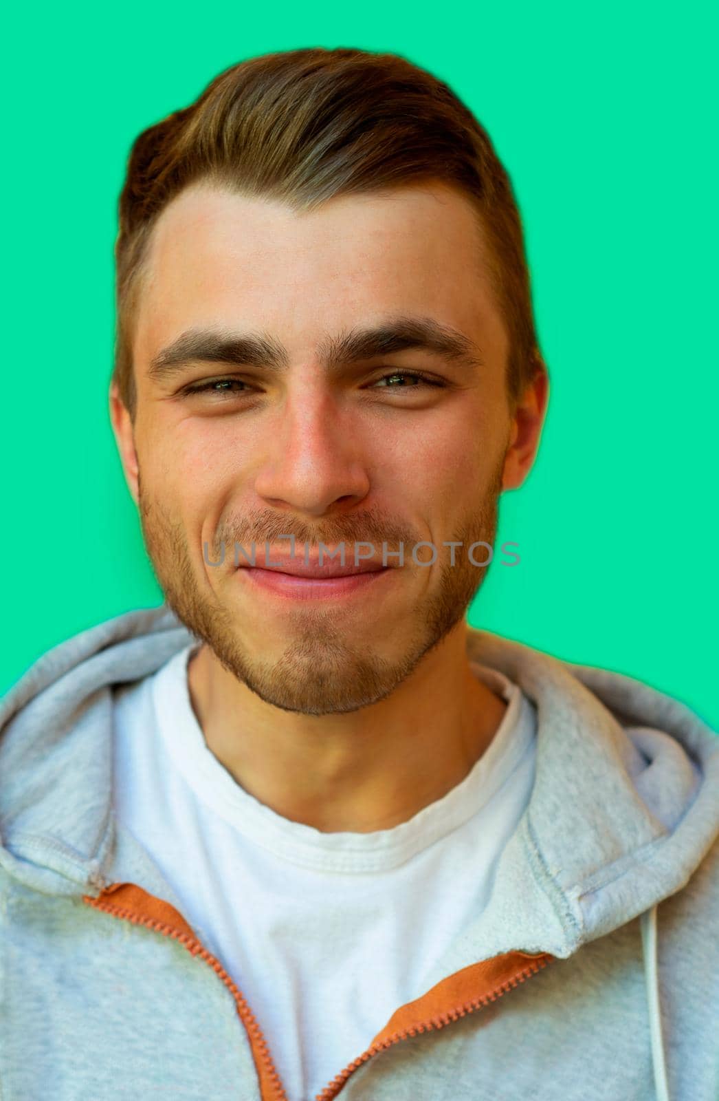 young hipster with a beard is smiling and looking at the camera on a neo mint color wall background.