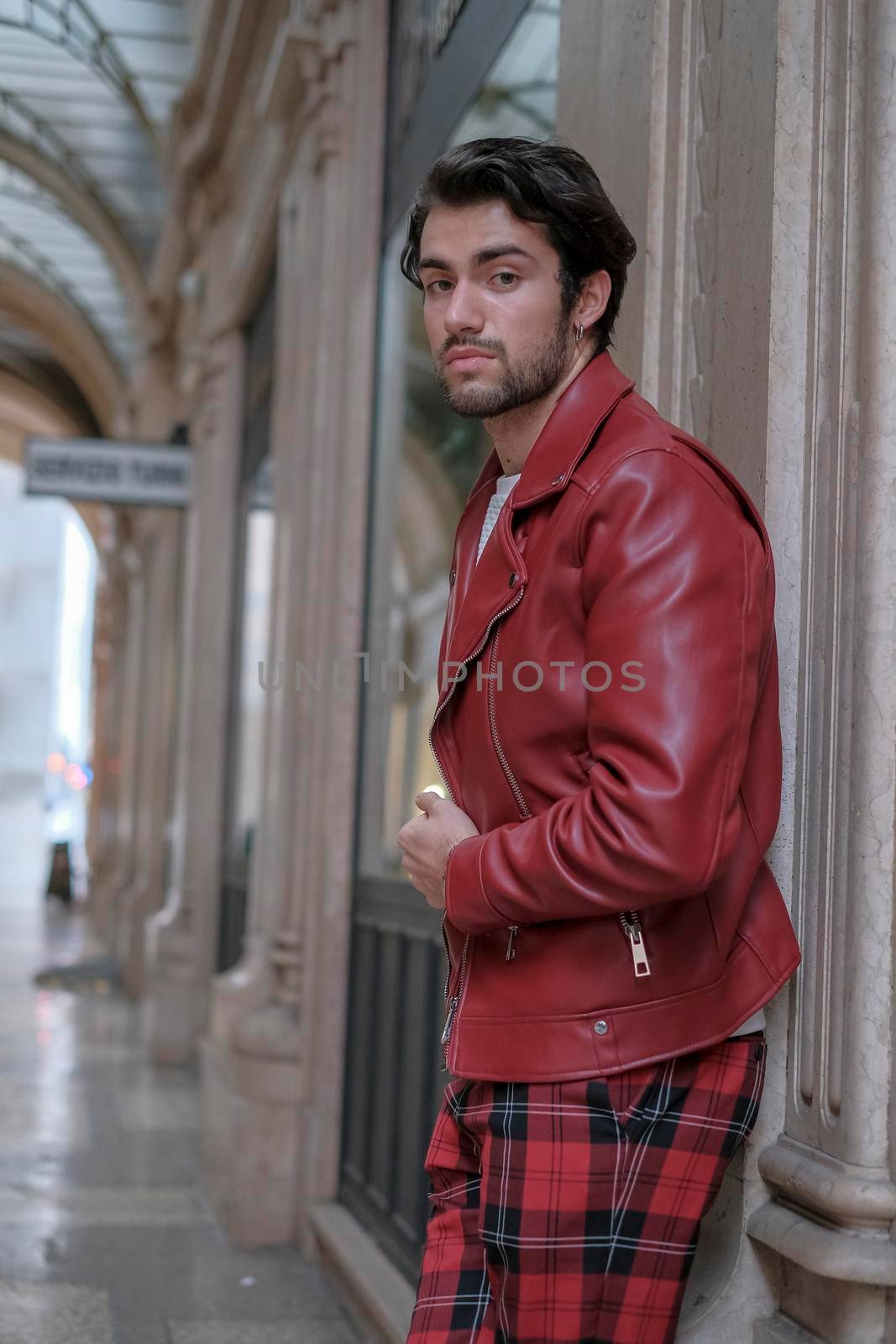 beautiful guy with red leather jacket and backpack in the center of reggio emilia. High quality photo