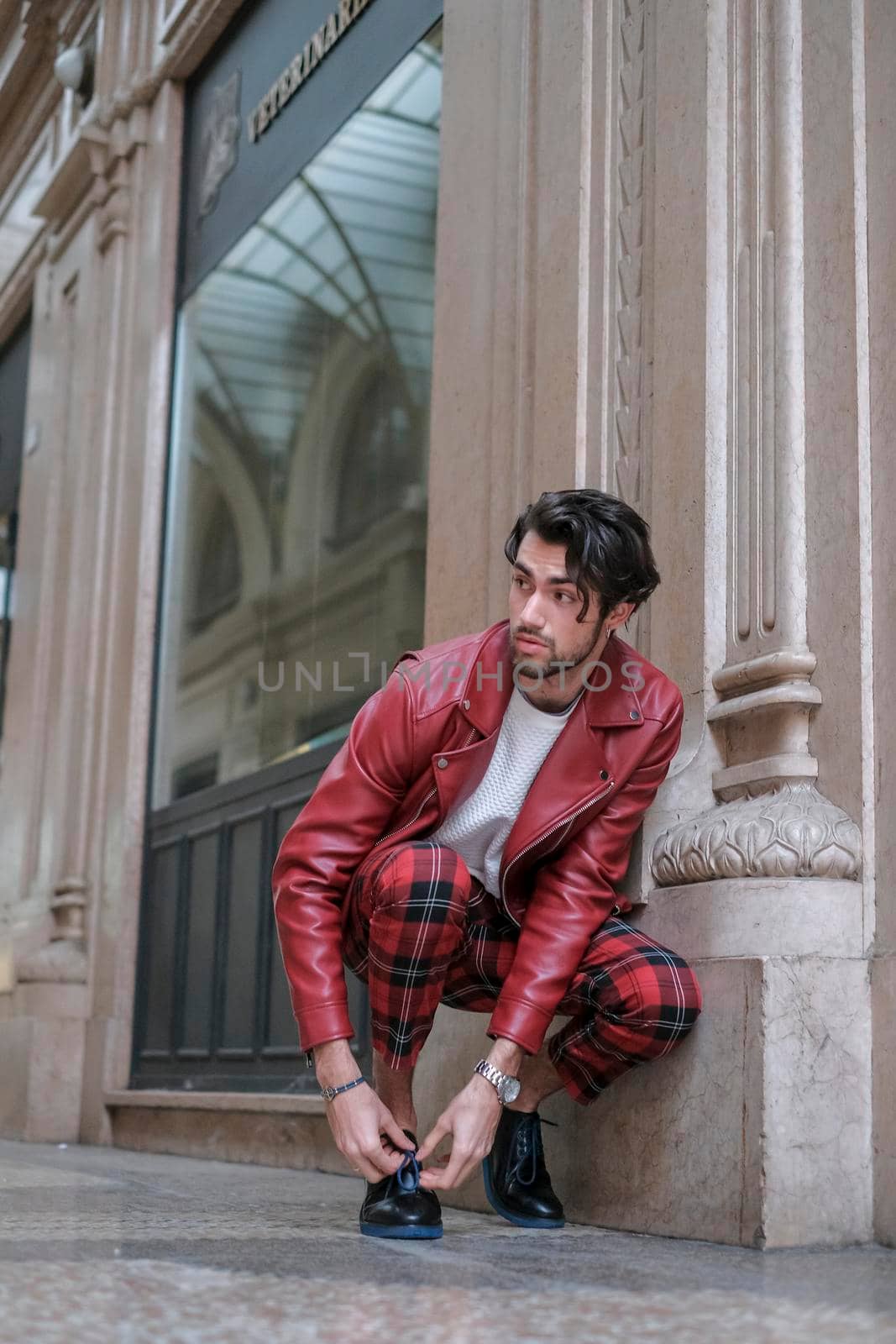 beautiful guy with red leather jacket and backpack in the center of reggio emilia. High quality photo