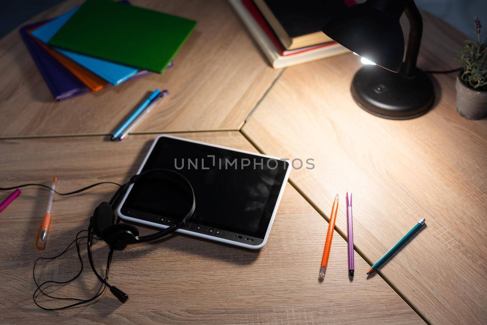 table with digital tablet with blank screen on table with colorful drawing supplies.