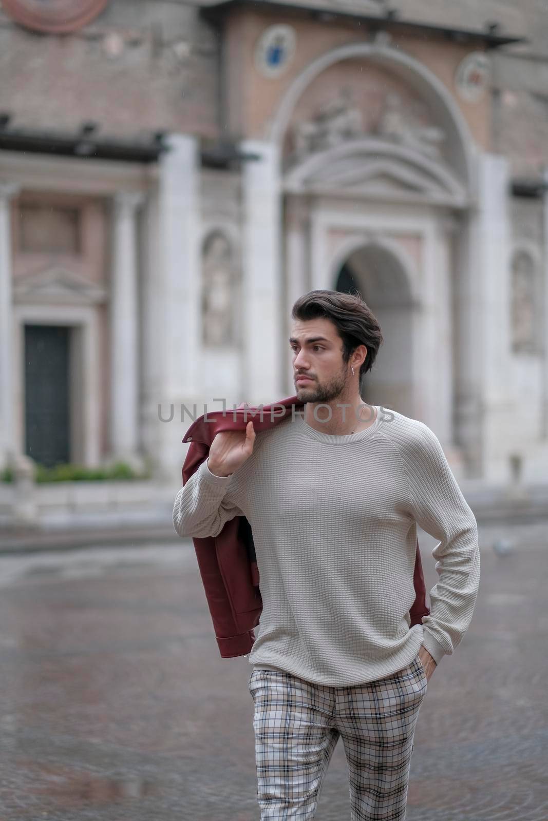 beautiful guy with red leather jacket and backpack in the center of reggio emilia. High quality photo