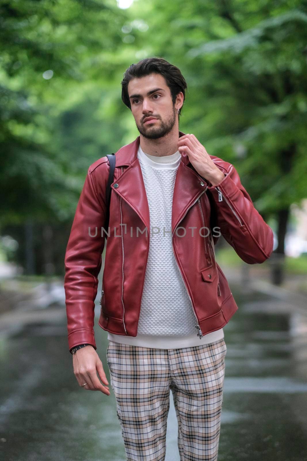 beautiful guy with red leather jacket and backpack in the center of reggio emilia. High quality photo