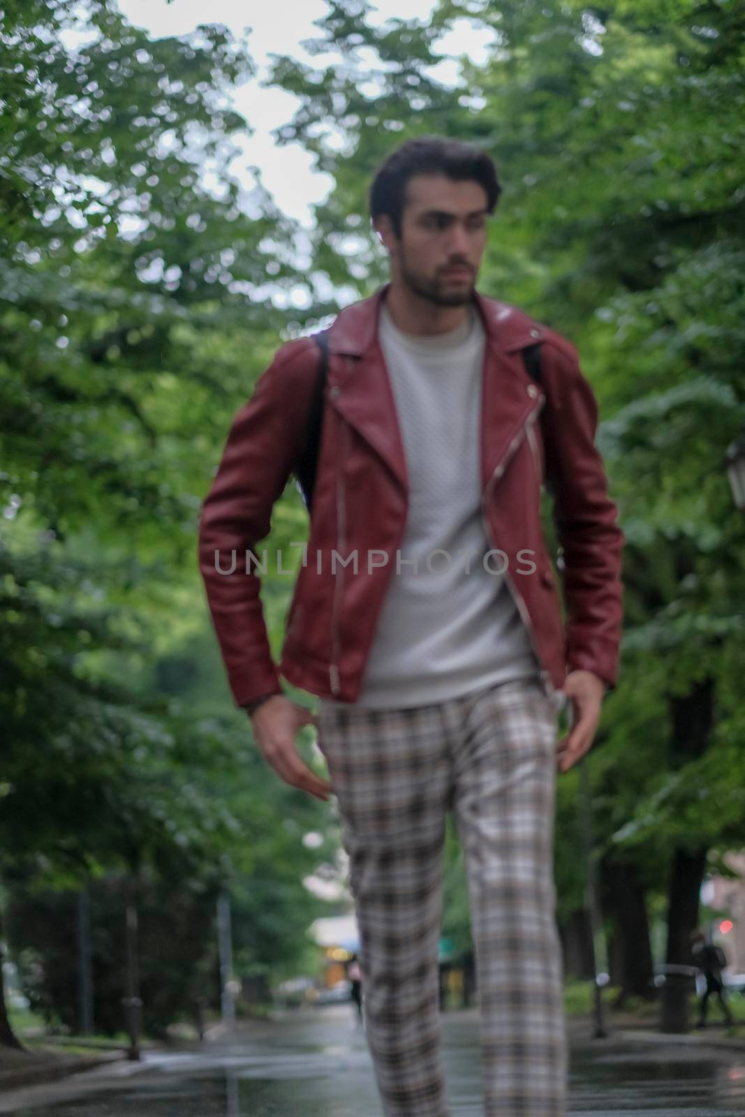 beautiful guy with red leather jacket and backpack in the center of reggio emilia. High quality photo