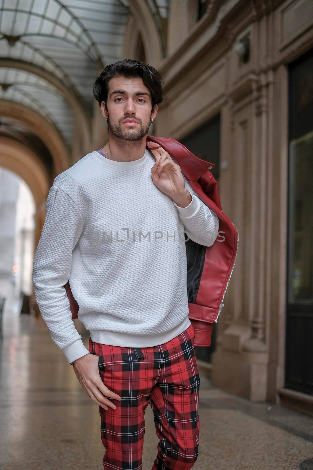 beautiful guy with red leather jacket and backpack in the center of reggio emilia. High quality photo