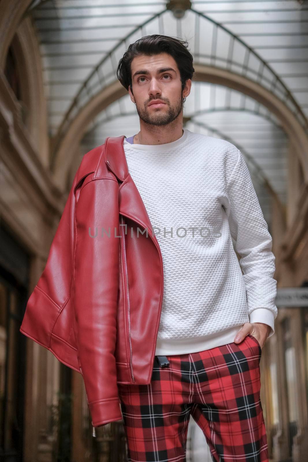 beautiful guy with red leather jacket and backpack in the center of reggio emilia. High quality photo