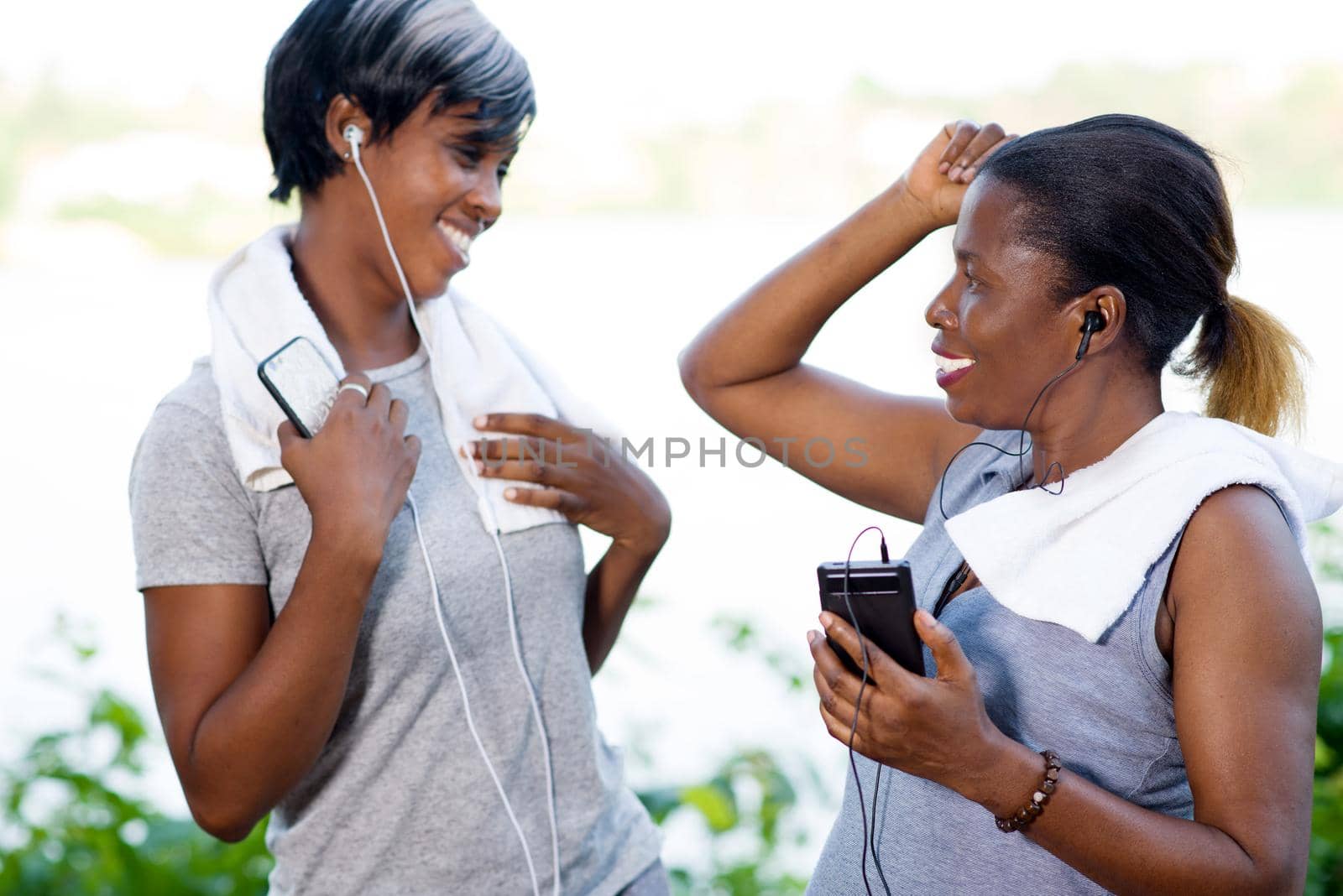young women standing listening to music after sport smiling.