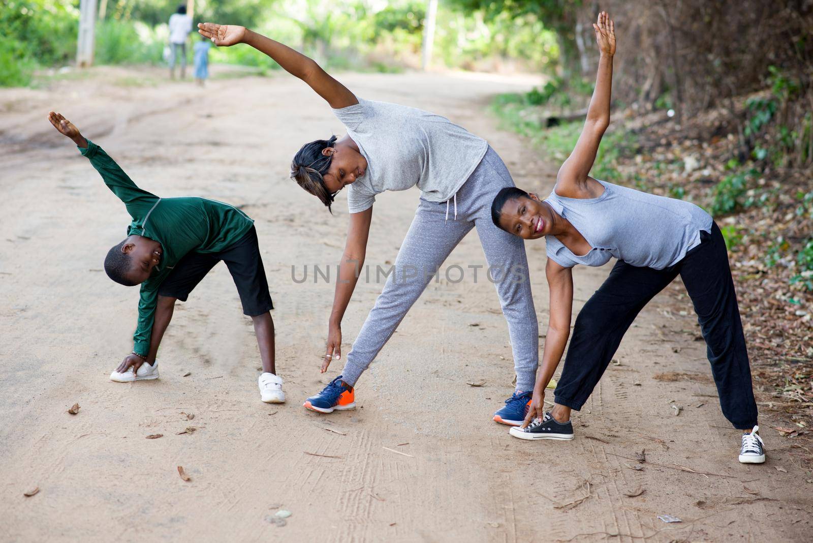 two active women with child in sportswear exercising stretching on the track in the park