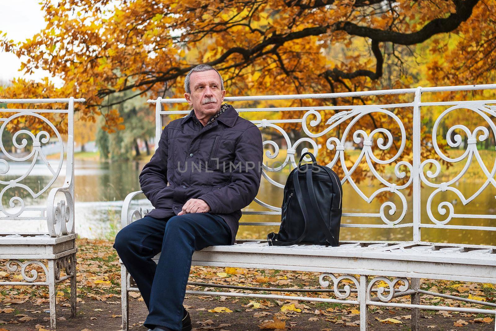 Boarder sits on a bench in a beautiful park near pond. by OlgaGubskaya