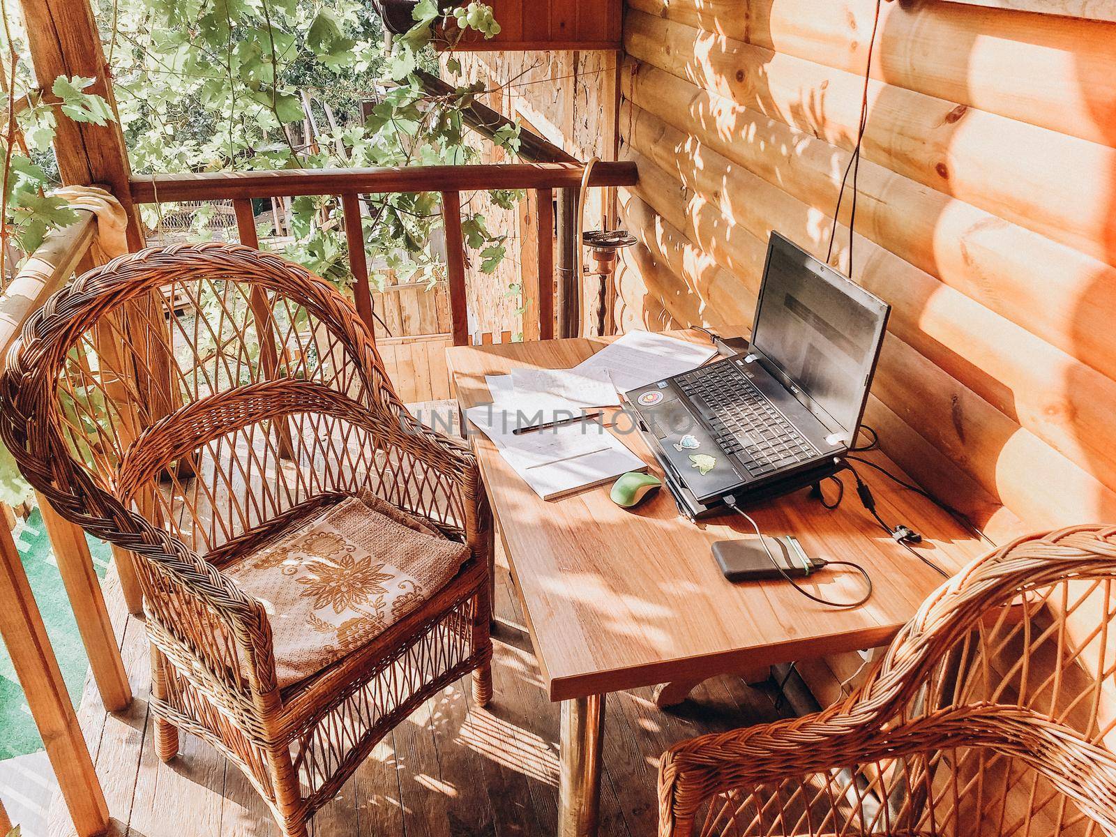 workplace in an open area in the garden with wicker furniture under the grapes. A place for a freelancer. The concept of free work.