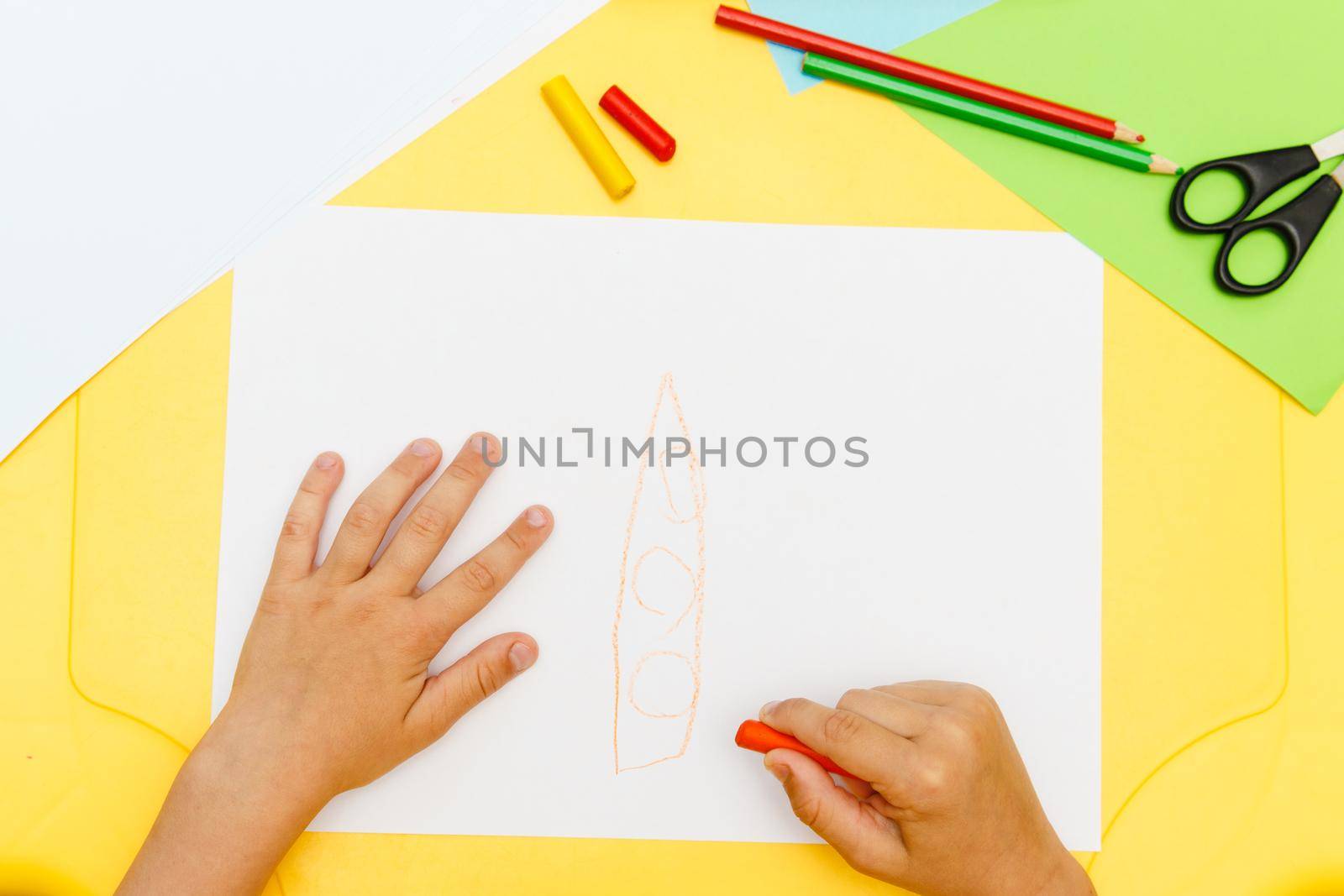 Indoor activity. Top view of kid's hands paiting with crayons. Indoor activity