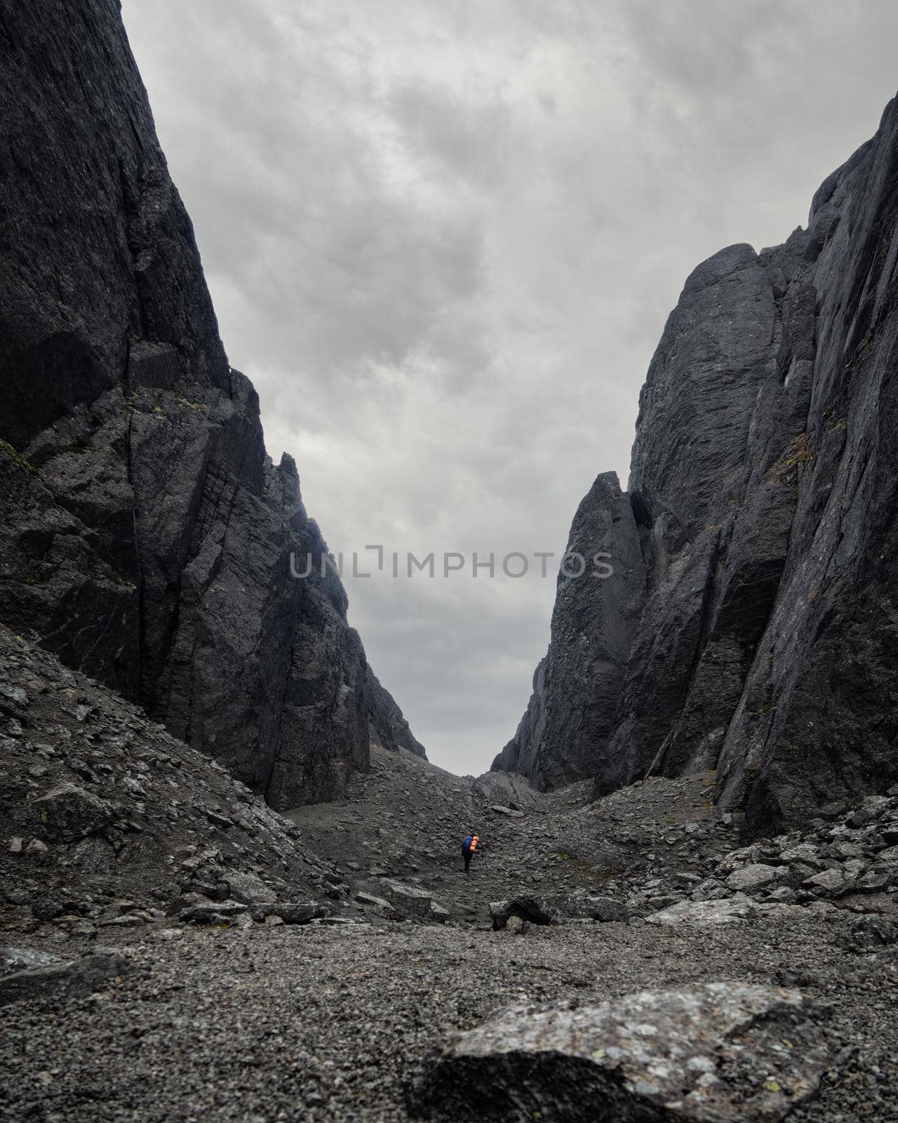 A young woman tourist with a backpack goes through a lifeless rocky pass. photo