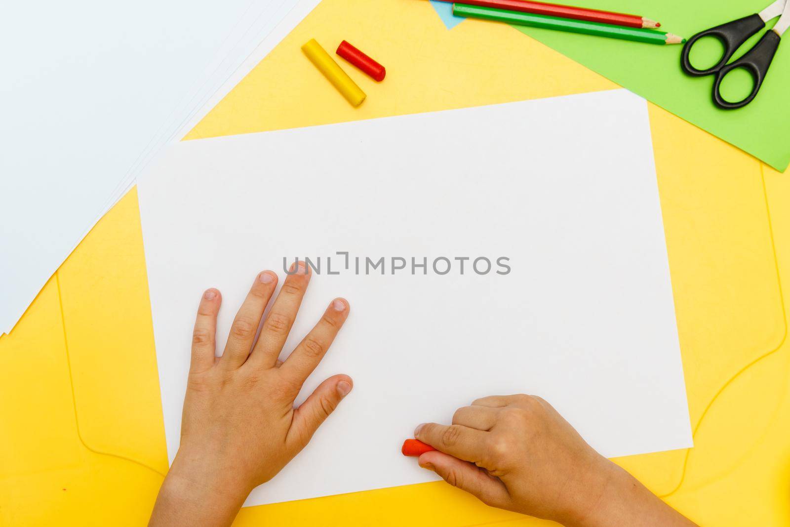 Indoor activity. Top view of kid's hands paiting with crayons. Indoor activity