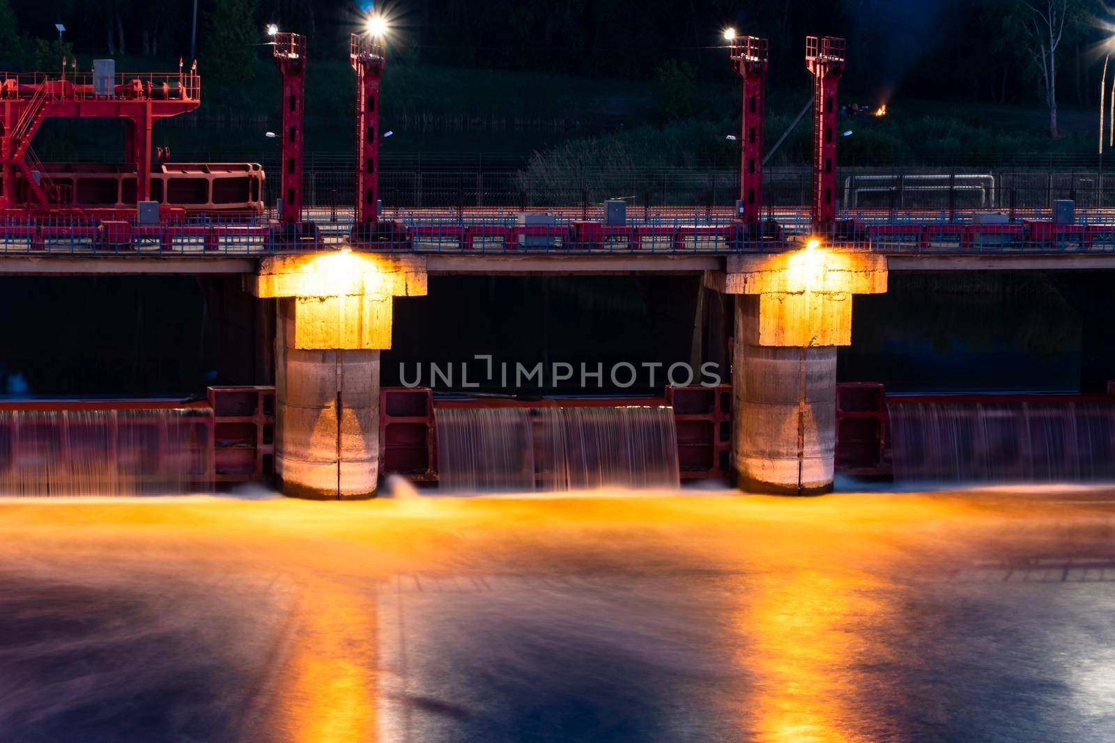 River,dam,bridge in the evening.Car and pedestrian bridge at night. A full-flowing river with a strong current.Clean,bubbling,fresh water.Technical construction on the river, fresh water reserves.