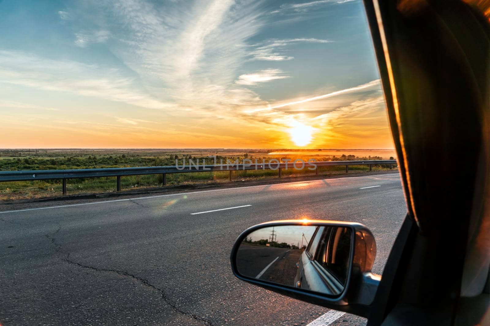 Evening trip to travel on the highway by car at sunset sunrise in the golden hour. Heavenly light.Dramatic evening sky with clouds and rays of the sun view from the window.Panoramic view of clouds by YevgeniySam