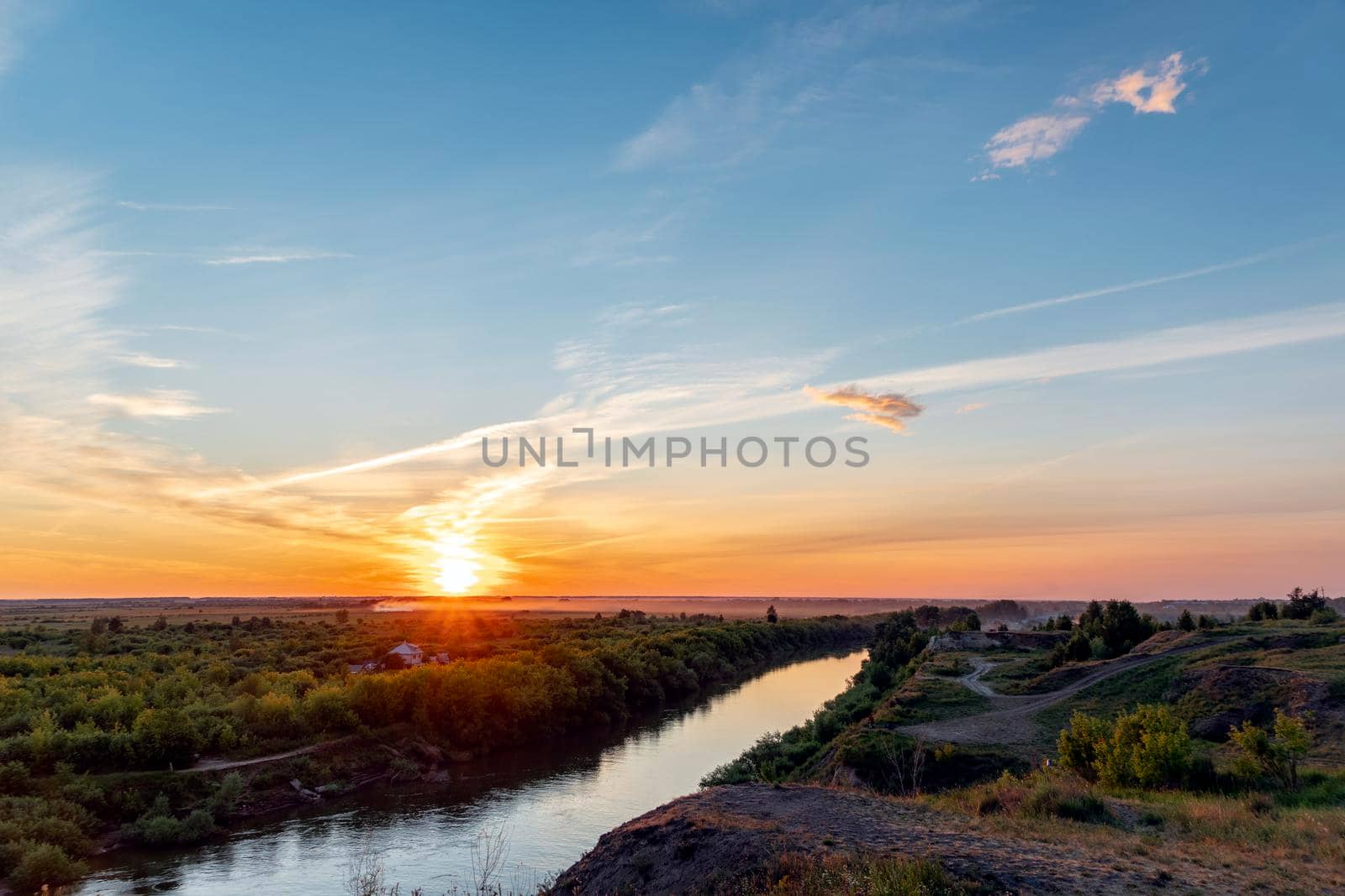 The heavenly light of the sun over the river and the forest.Dramatic evening sky with clouds and rays of the sun.Golden hour at evening sunset or morning sunrise.Panoramic view of cirrus clouds by YevgeniySam
