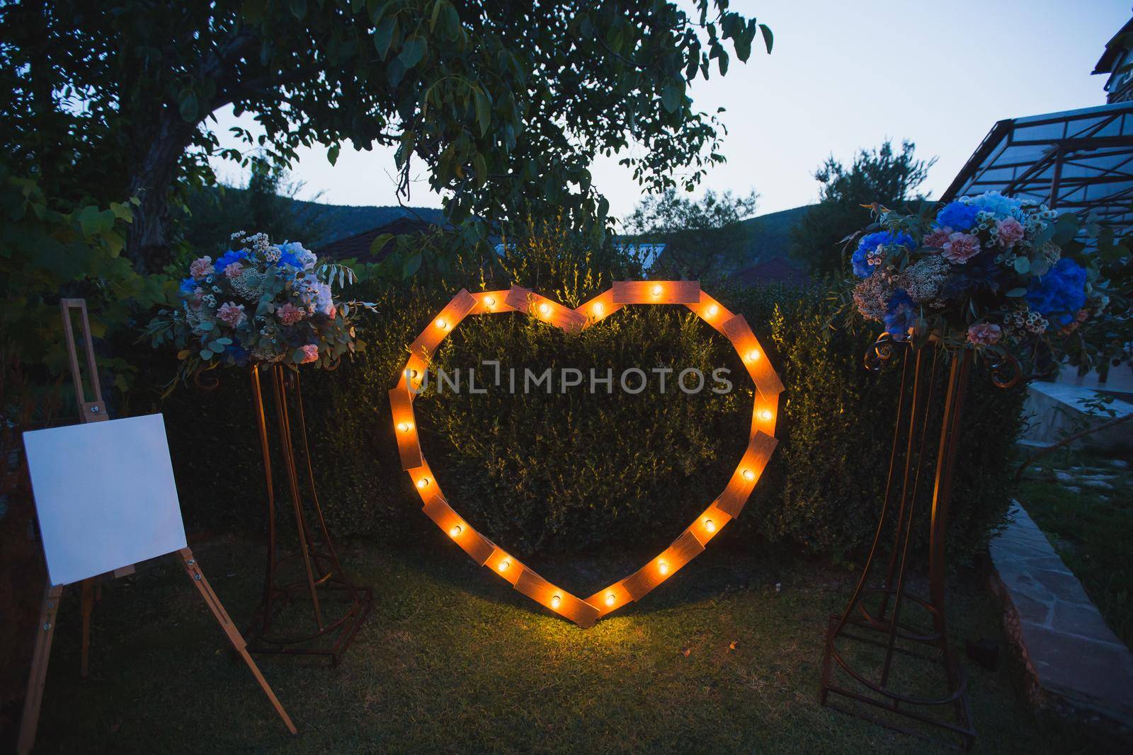 Handmade heart illuminated by light bulbs at a wedding. by StudioPeace