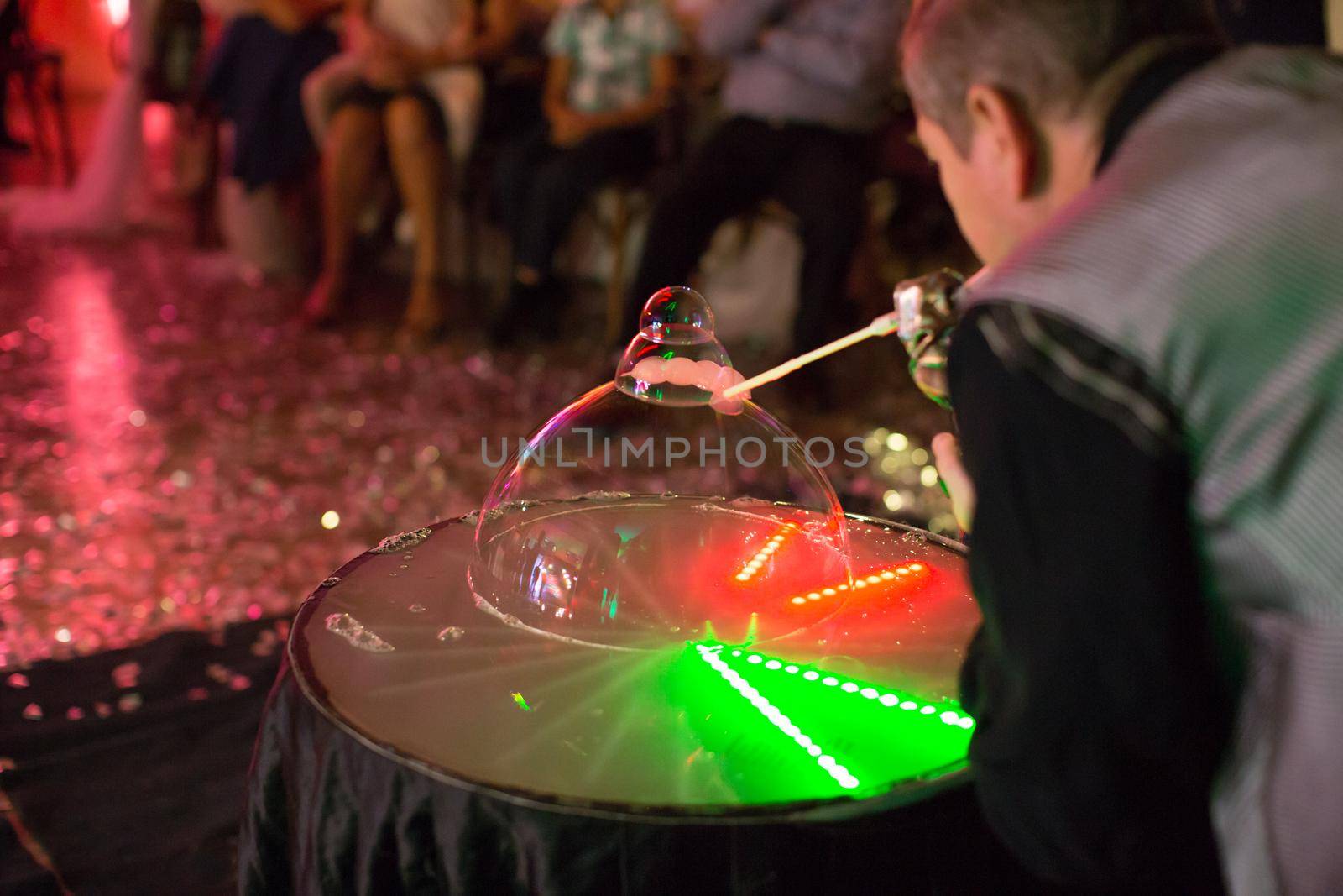 Bubble show at the event. A man inflates a soap balloon.