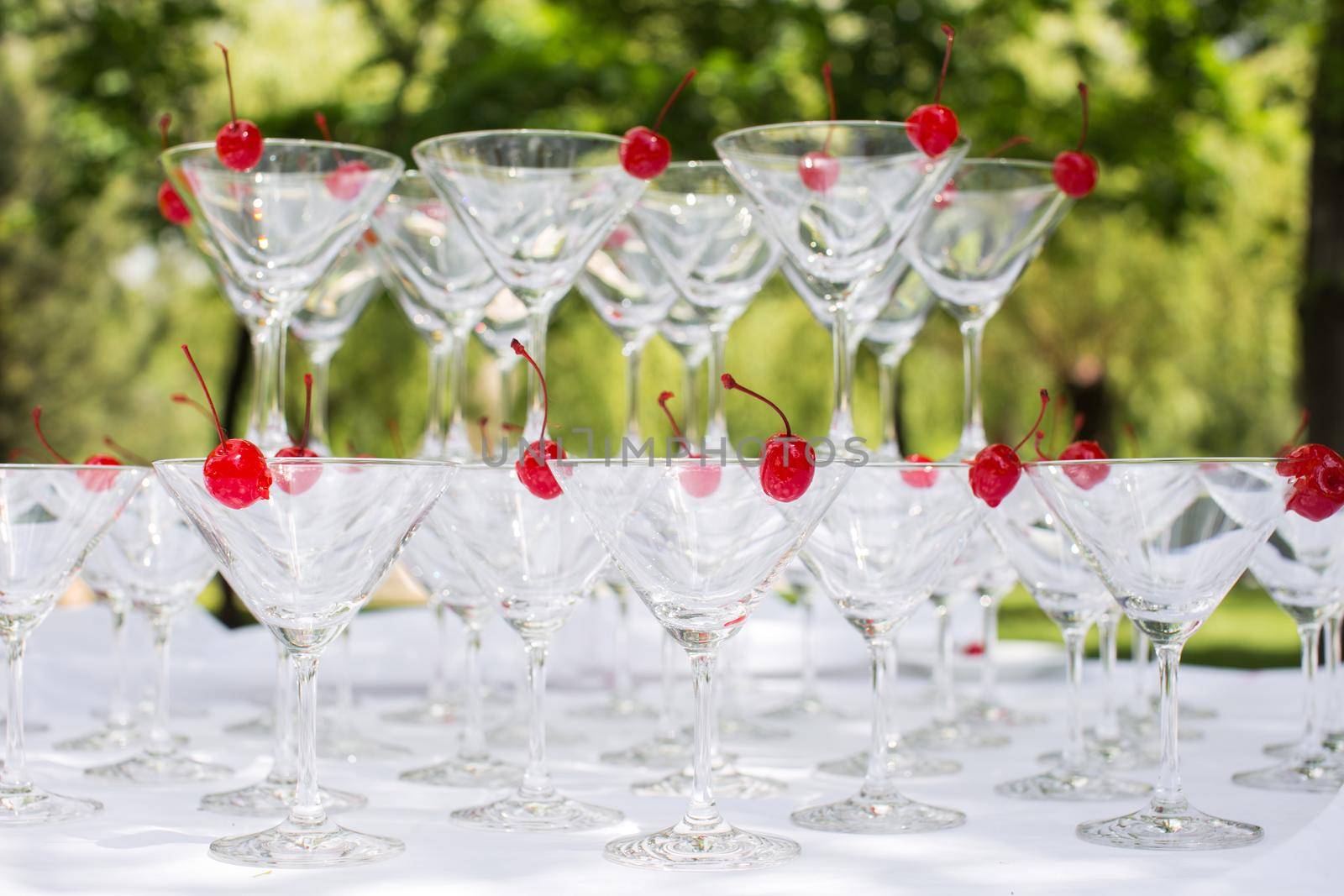 Close-up of the champagne pyramid with a red cherry at the top of each glassGlass goblets. Pyramid of champagne. A celebratory drink. Decorations for the Banquet by StudioPeace