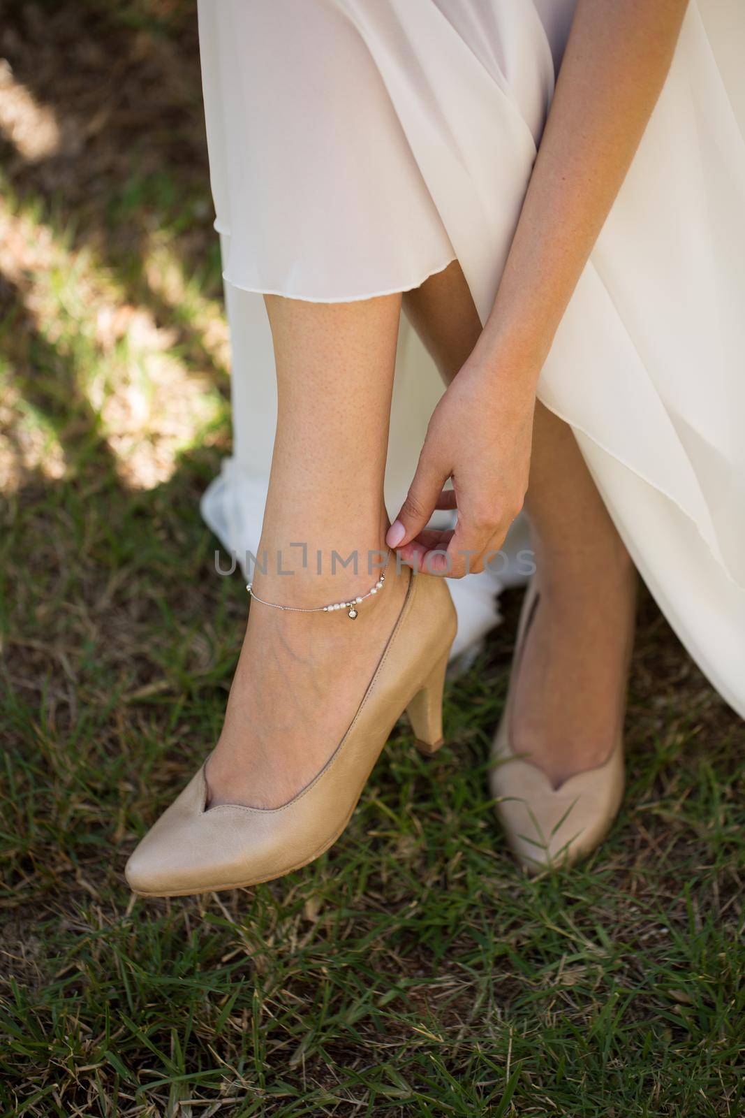 The bride puts a wedding decoration on her leg