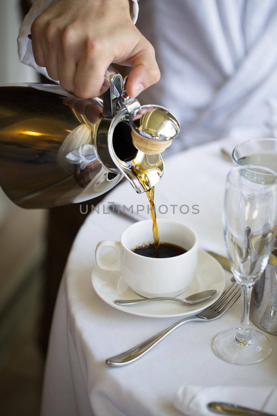 A man pours coffee into a cup at home. by StudioPeace