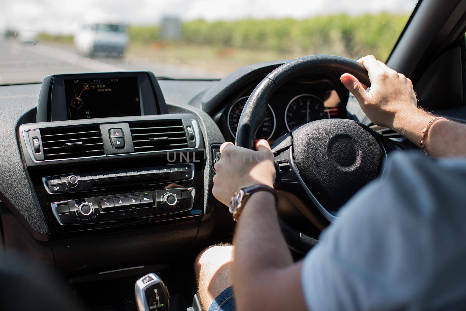 Men's hands on the steering wheel. A man is traveling in his car by StudioPeace