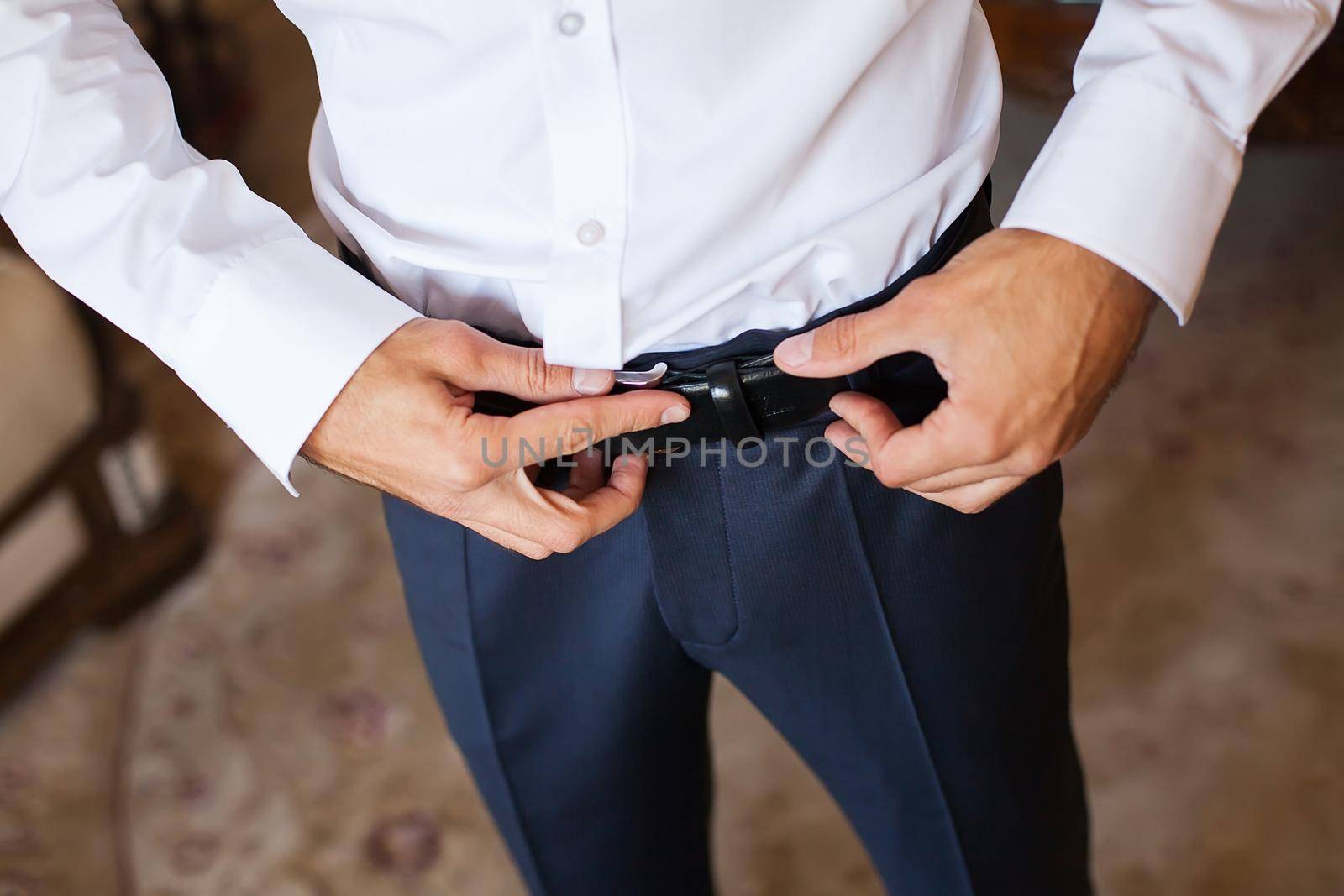 Man corrects belt, fees groom, man's hands, dressing, man buttons pants, jeans. by StudioPeace