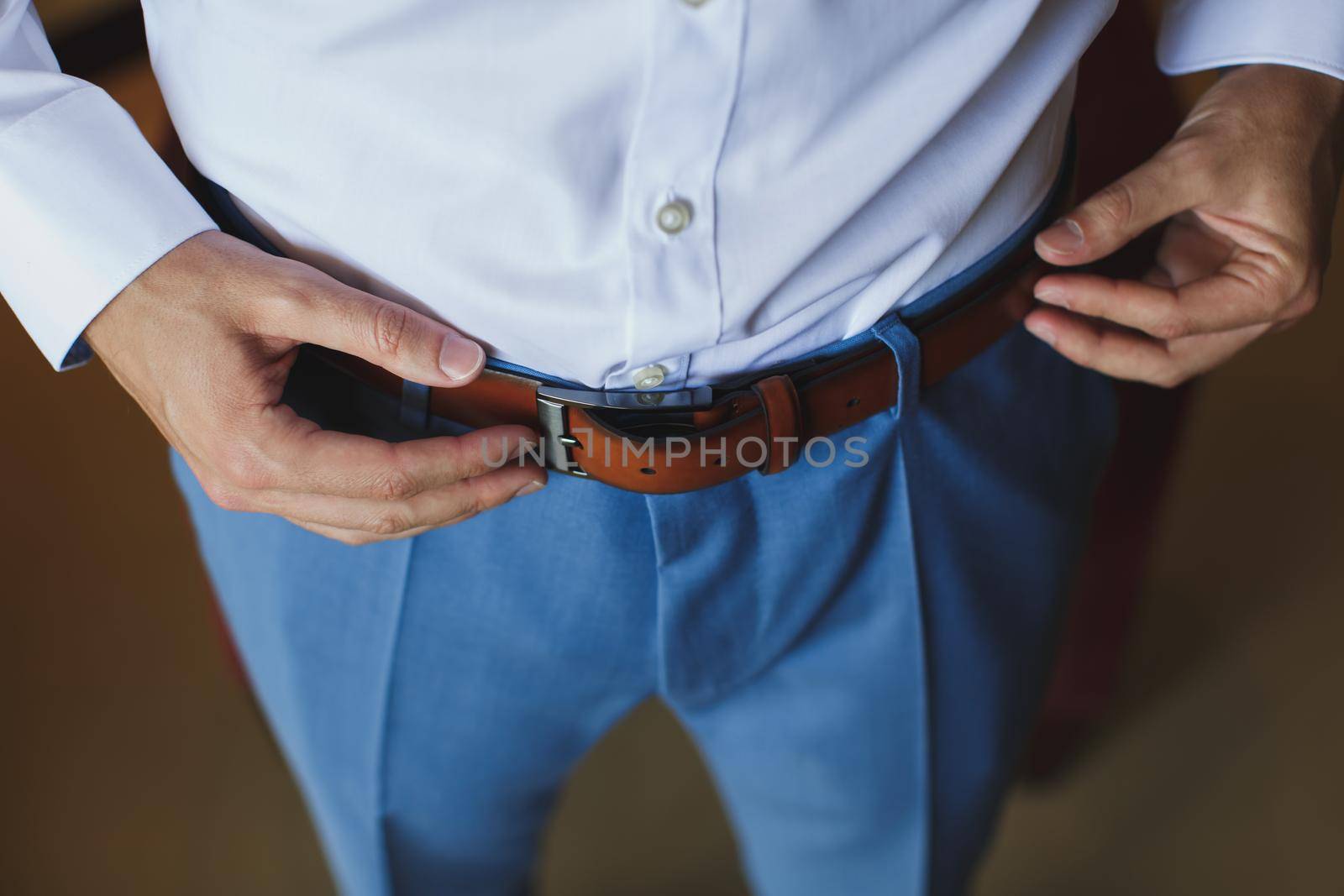 Man corrects belt, fees groom, man's hands, dressing, man buttons pants, jeans