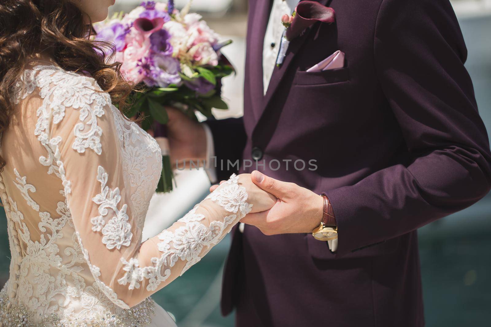 Close-up of the groom holding the bride's hand during the ceremony.