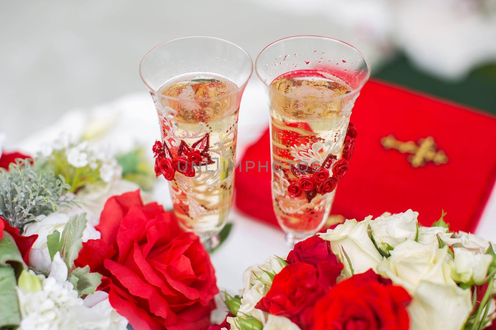 The champagne glasses. Wedding ceremony outdoors. Bouquet with red flowers.