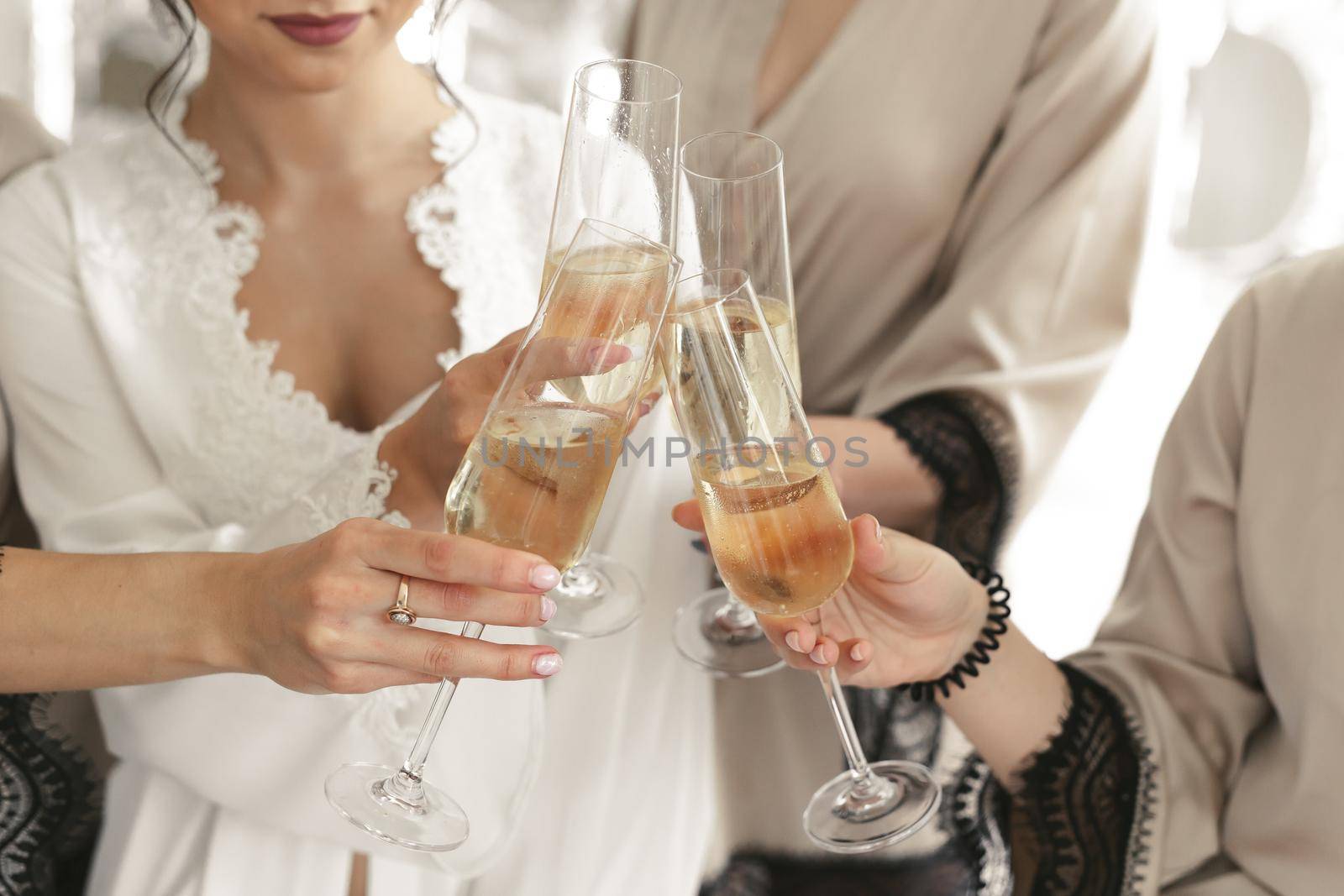 The bride and groom hold crystal glasses filled with champagne. by StudioPeace