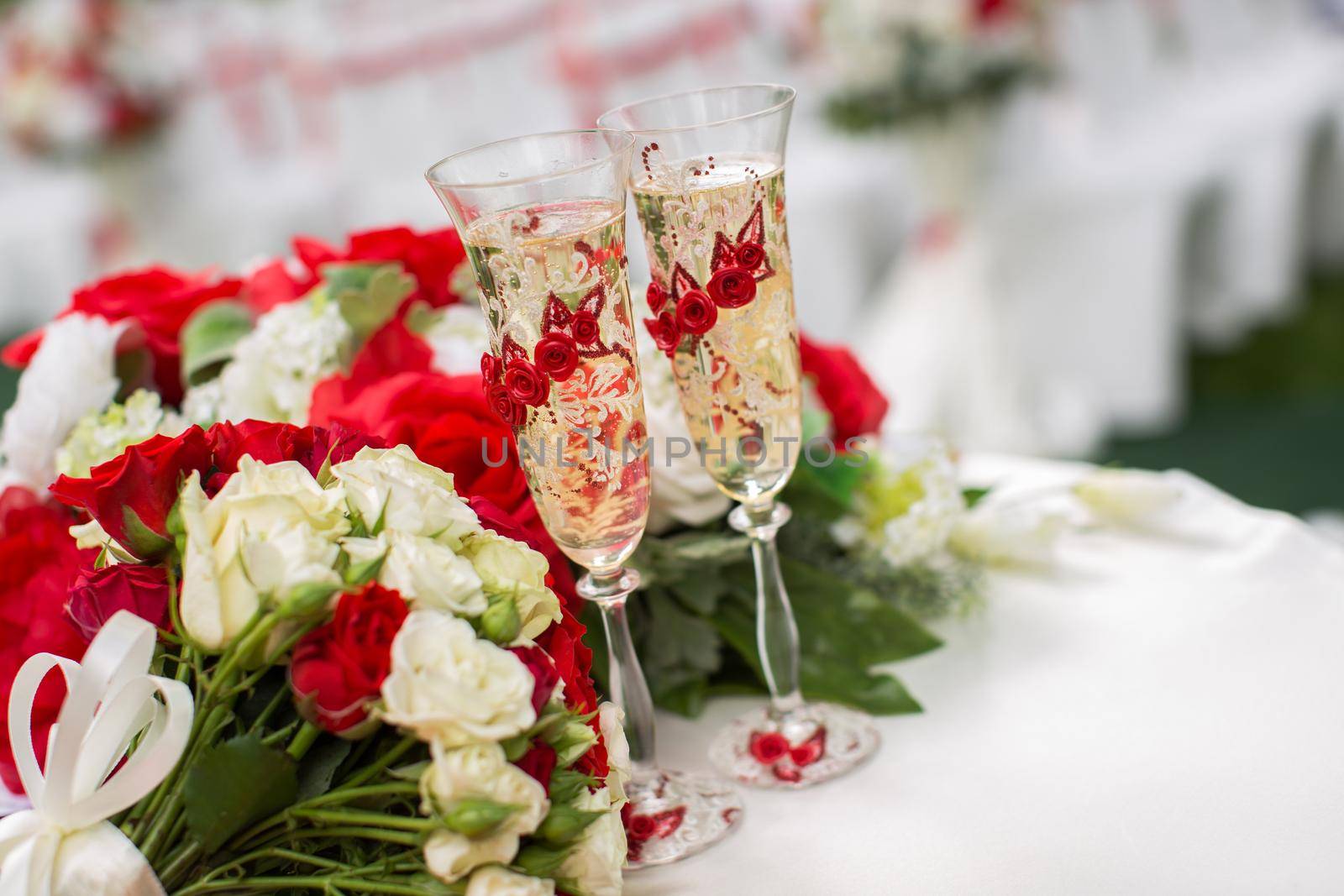 The champagne glasses. Wedding ceremony outdoors. Bouquet with red flowers.