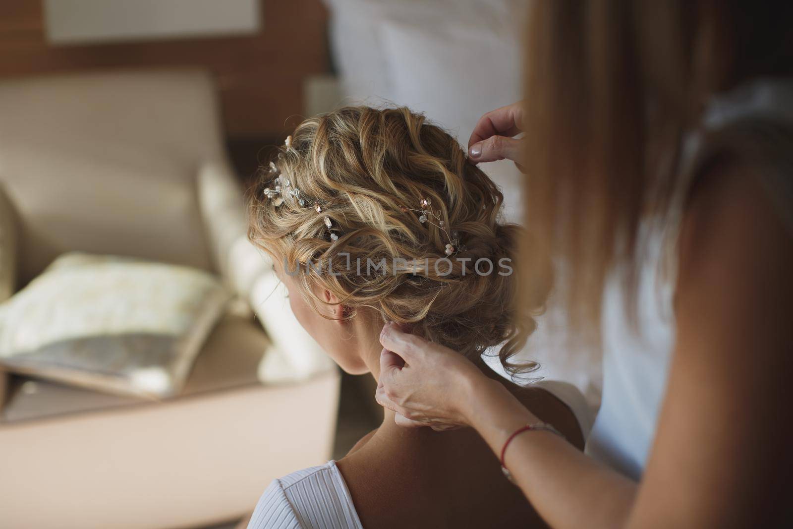 The stylist does the bride's hair at the hotel. by StudioPeace