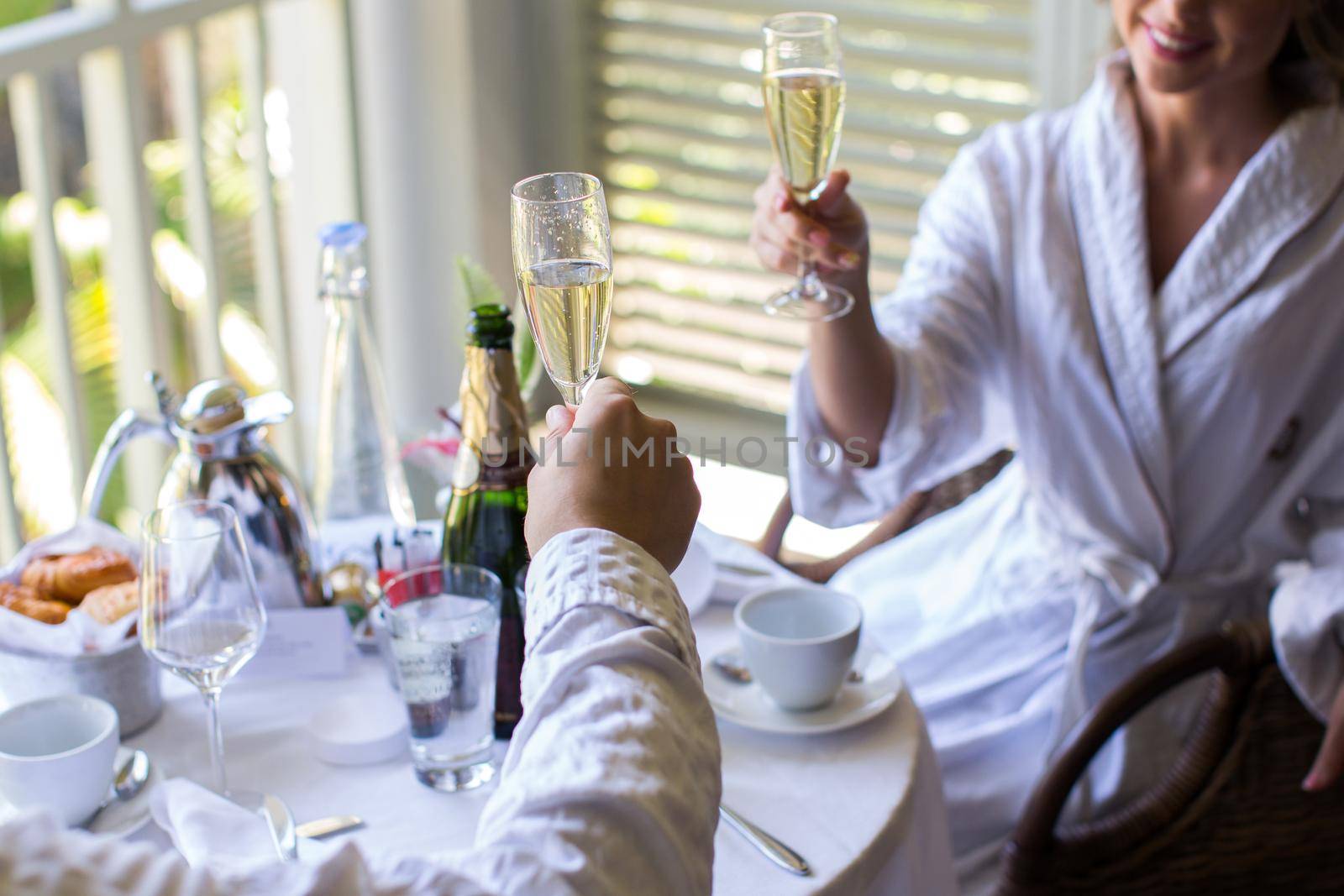 A couple in dressing gowns in a hotel drinking champagne